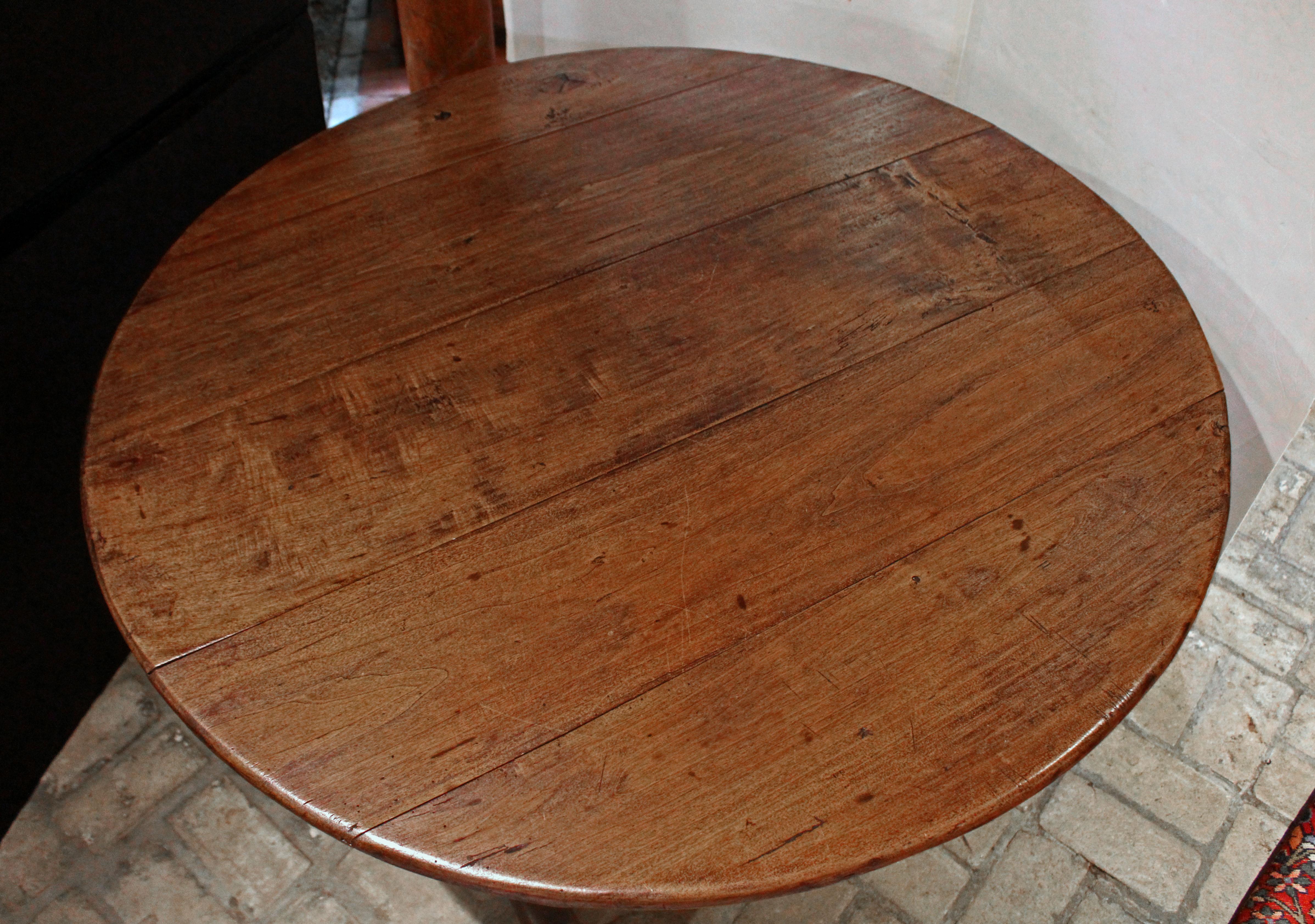 Circa 1830 country French round tilt-top wine tasting table or vintner's table. Raised on bold, shoe feet with wishbone swivel support to open. Warm hard poplar with chestnut battens. One foot with small area of old wood worm loss.
43