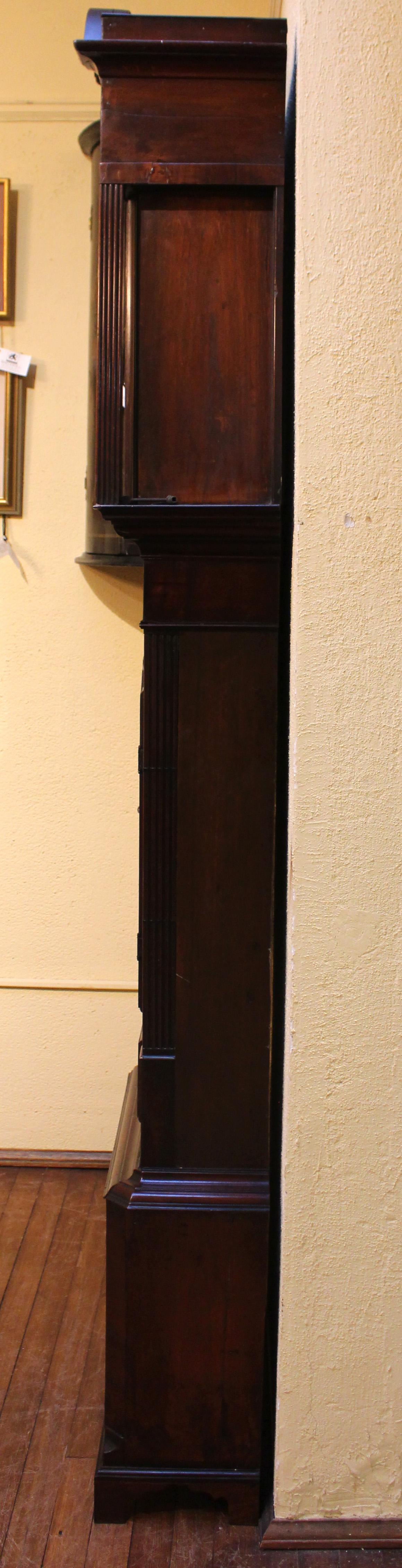 Circa 1830 Georgian tall case clock. Gothic waist panel & boldly reeded square pilasters, partially stopped by ebony line inlays. Exceptional choice of mahogany veneers & solids. Broken arch pediment with carved rondels. Double crown molding, the
