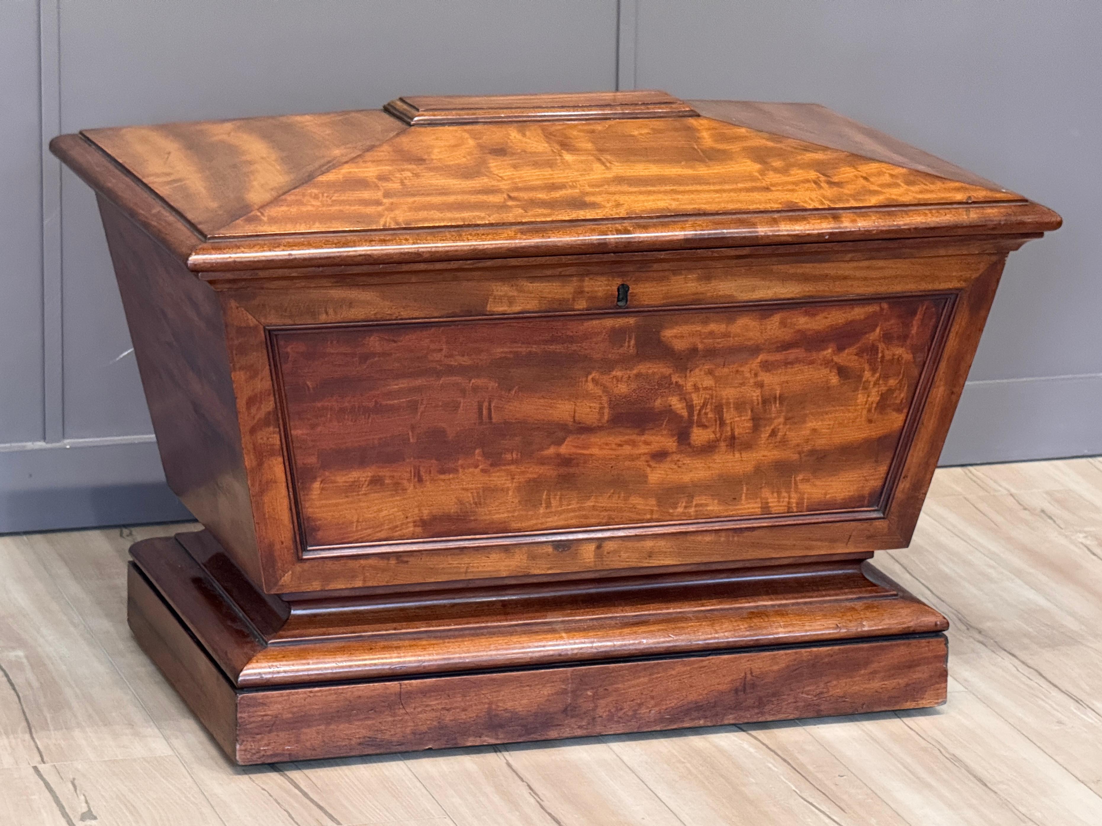 A very fine English Regency period cellarette in sarcophagus form, circa 1830. Retains its original zinc liner along with a fitted, zinc-lined interior lid. Beautifully shaped with panelled sides and stepped plinth base