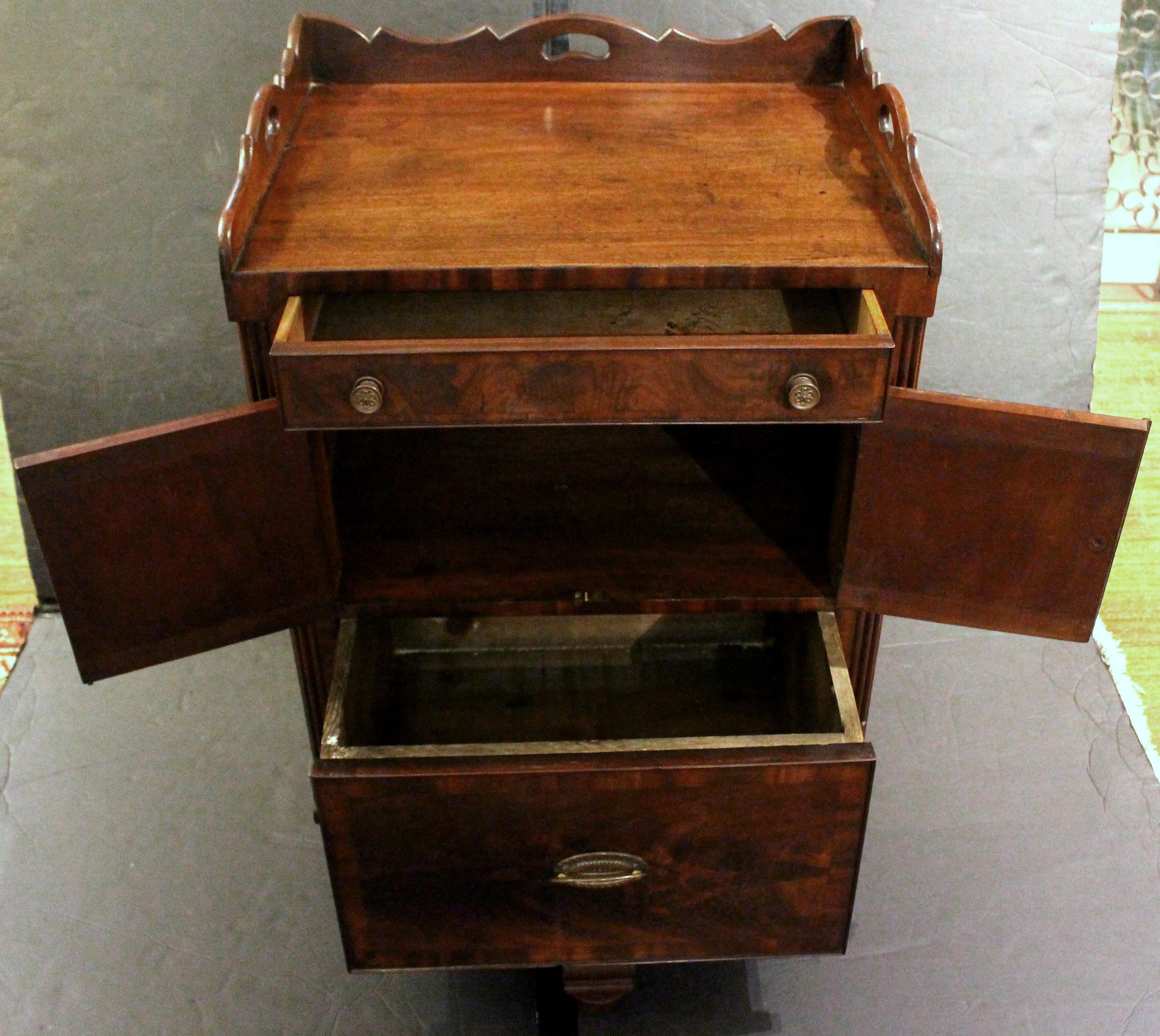 Circa 1830 George IV-William IV period bedside cabinet commode. The lower section now as a drawer rather than a chamber pot holder. Mahogany with oak secondary wood. Well shaped gallery top with handle cut-outs for moving. Reeded cluster columns