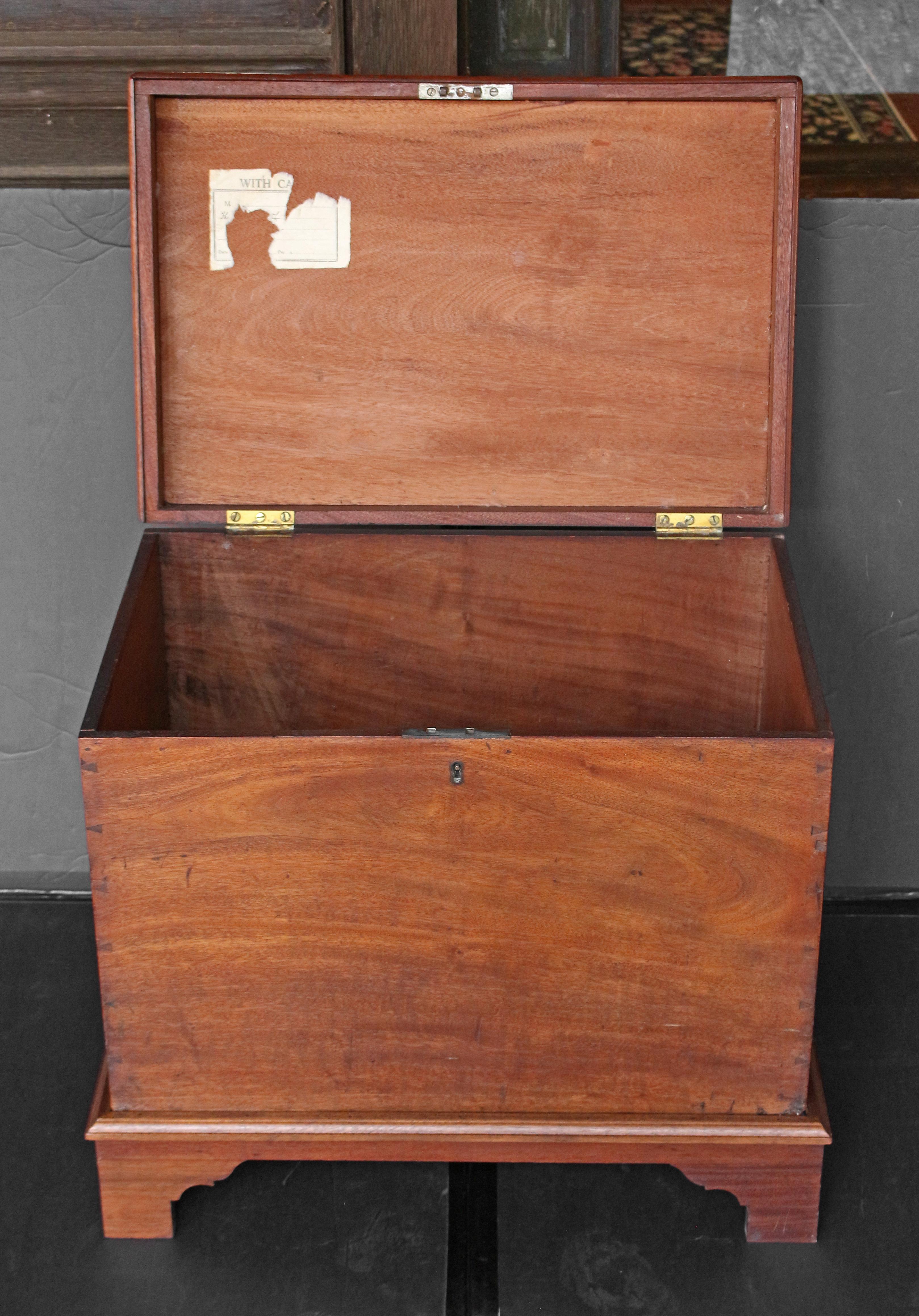 Circa 1830 late Georgian travel chest, on later stand, English. Mahogany of good color with heavy bail & rosette brass handles. Well made dovetails visible as part of the decoration of the piece. Now on bracket footed base. Ideal as a side table or