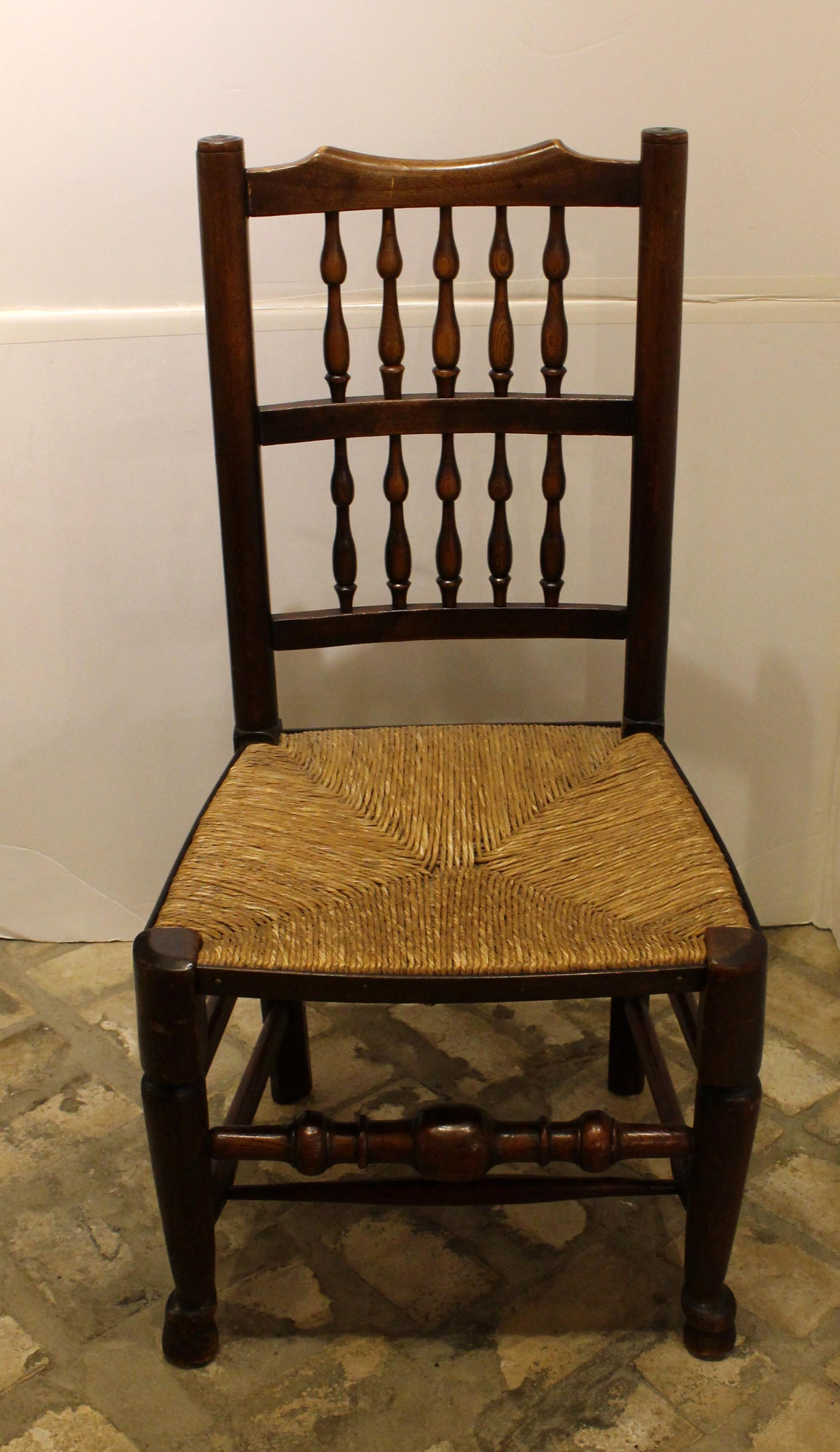 circa 1830 set of 8 English country dining chairs, Lancashire. Spindleback side chairs of ash & elm. Rush seats in good condition given age & use, some reworked. Nice color & patina. As is usual, an associated set with charming variations amongst