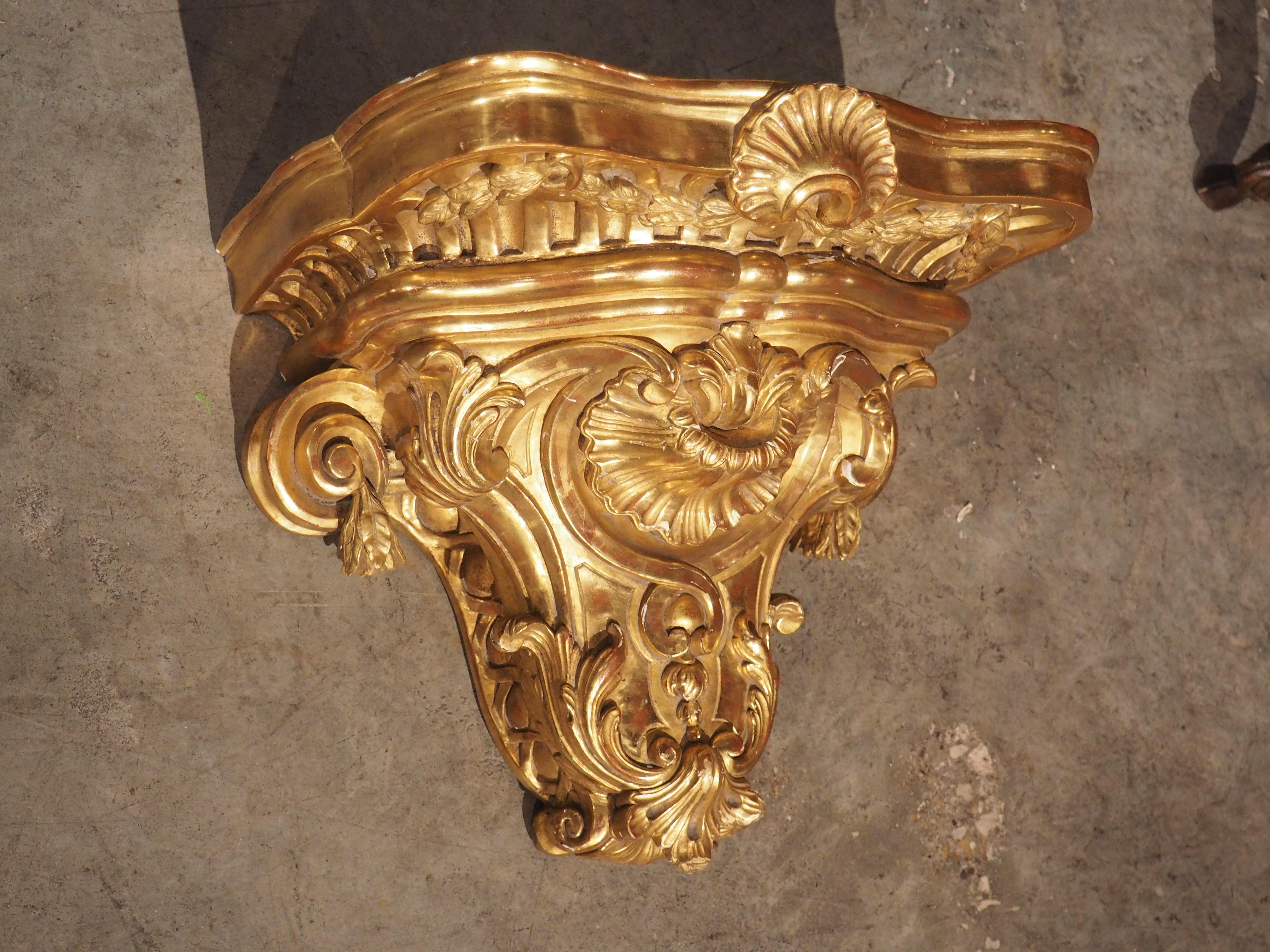 Diese um 1850 in Frankreich handgeschnitzte, elegante Etagere weist von der Natur inspirierte Elemente auf, die als Rocaille-Stil bekannt sind. Das opulente Wandregal aus vergoldetem Holz weist eine reiche und lebendige Patina auf, mit
