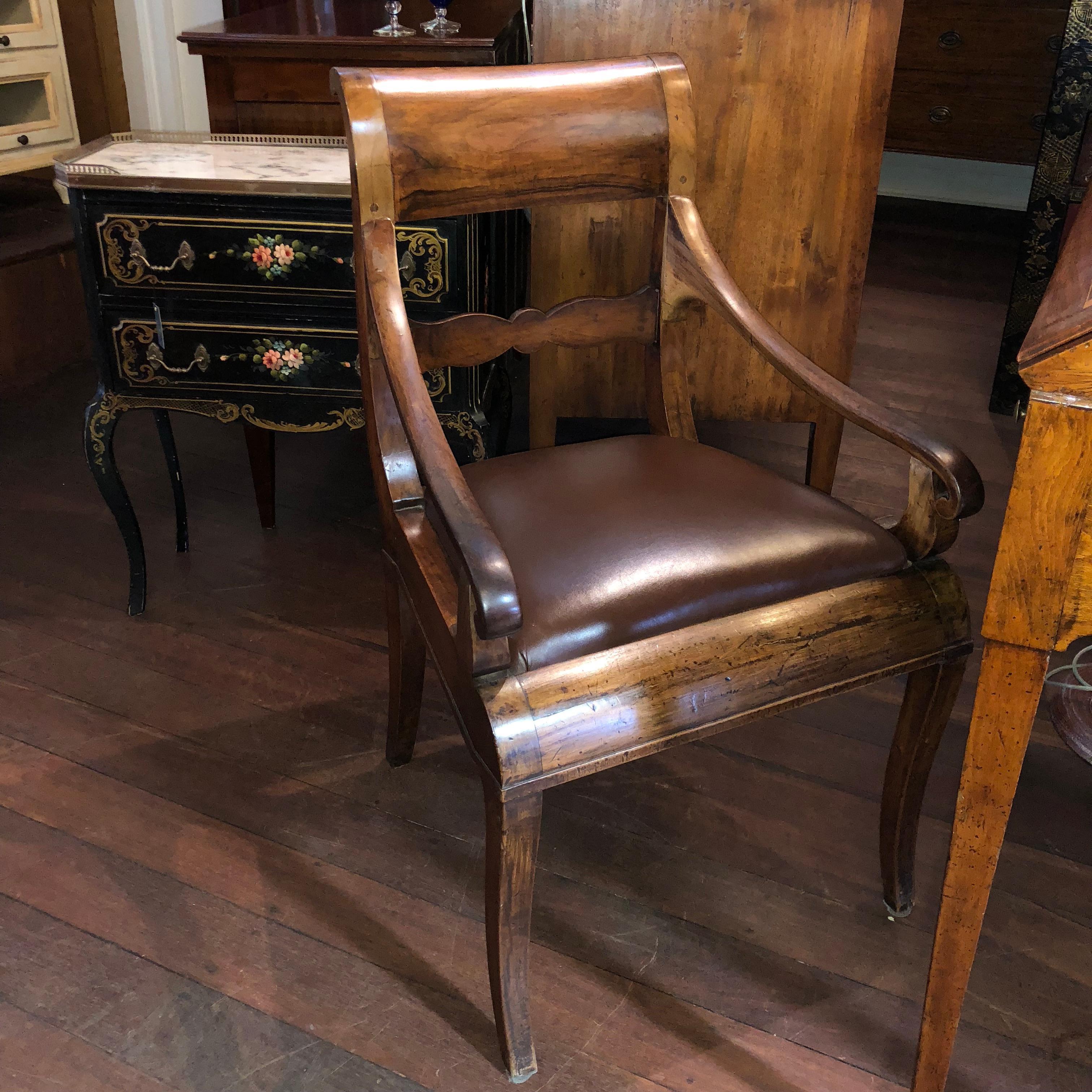 This sensational Italian walnut chair has been dated at mid 19th Century and features curved, scroll top ladder-back and delicately scrolled arms. The seat has been later re-upholstered with soft Italian brown leather, allowing for great