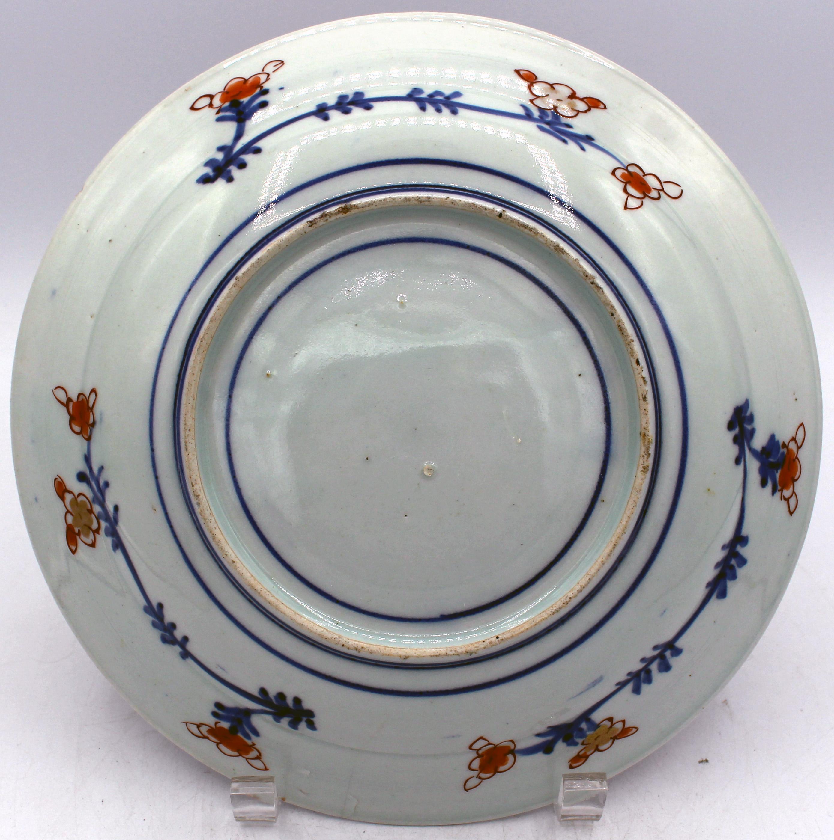 Circa 1850 Japanese Imari Deep Low Bowl or Plate. Underglaze blue with iron red/orange & gilt overglaze. A splendid jardiniere of peonies & chrysanthemums sits on a trellised veranda. The border features alternating panels of plump white rabbits &