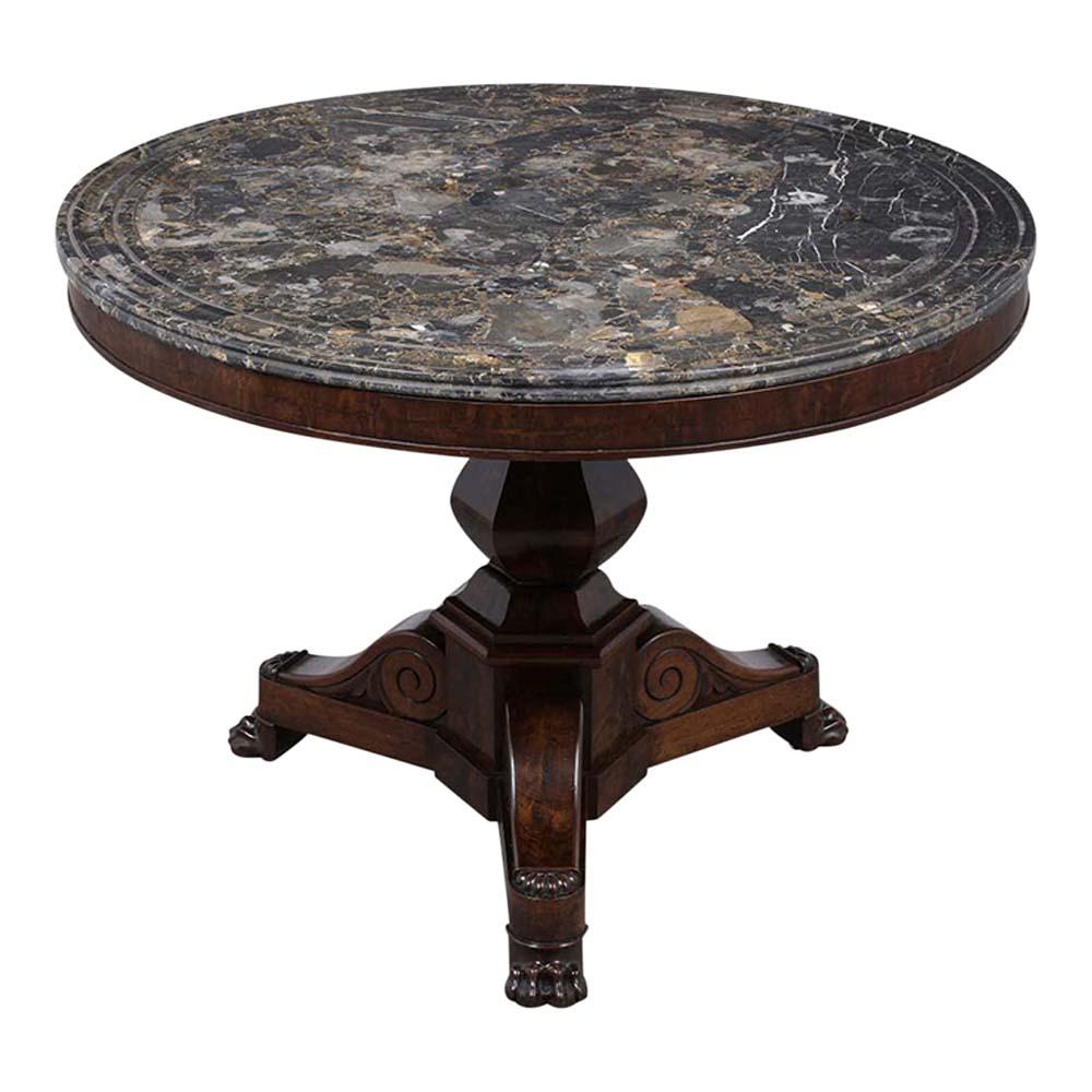 An 1850’s French Empire Round Center Table that is made of mahogany wood covered in burl veneers, and stained a rich mahogany color with a patinated finish. This table has a dark grey marble top with a beveled edge, engraved details on the top, and