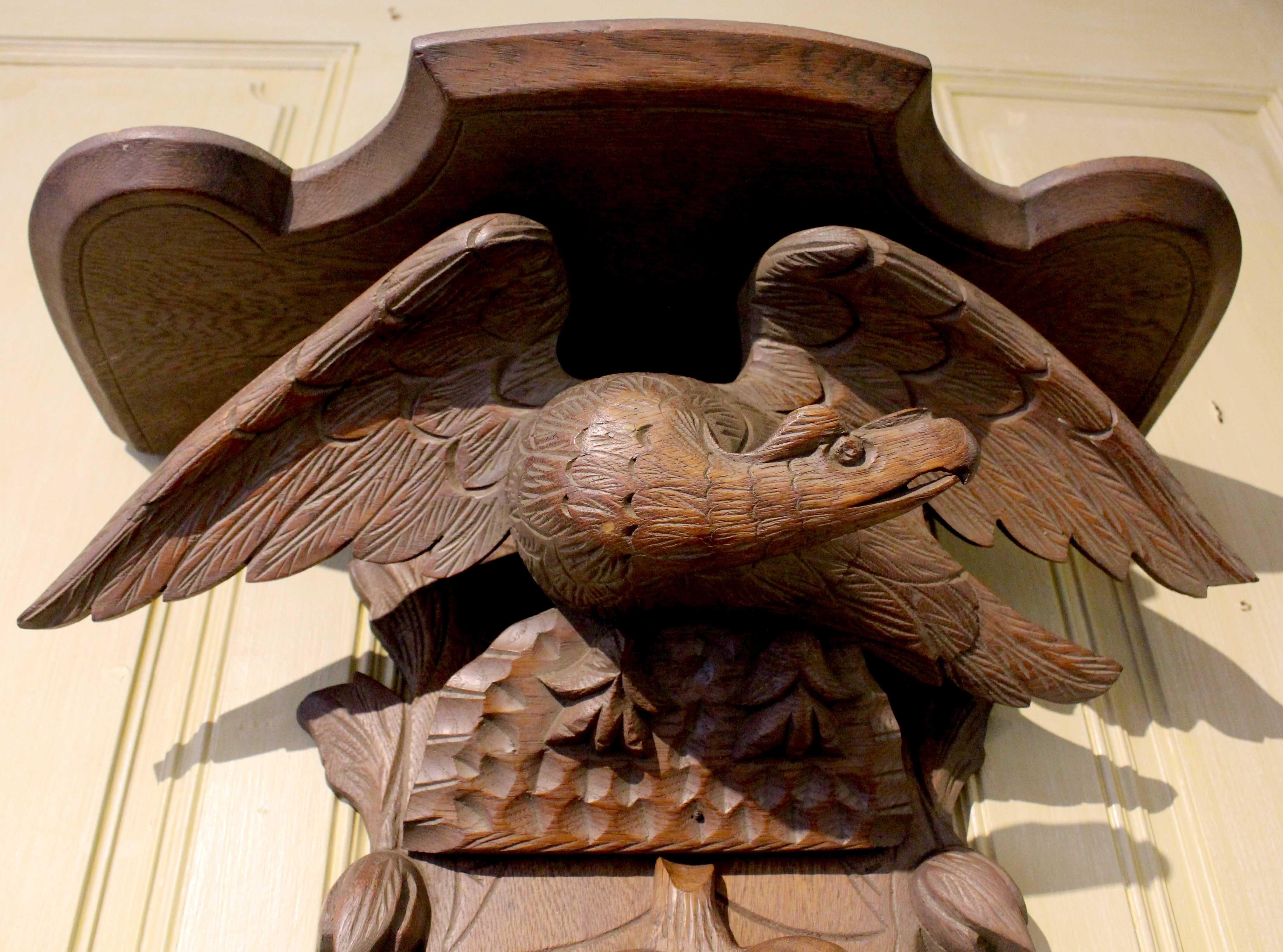 A boldly carved eagle wall shelf, c.1860-80, Black Forest. Carved from linden wood. Beneath the shelf a spread eagle above a festoon of fruits & leaves.
24