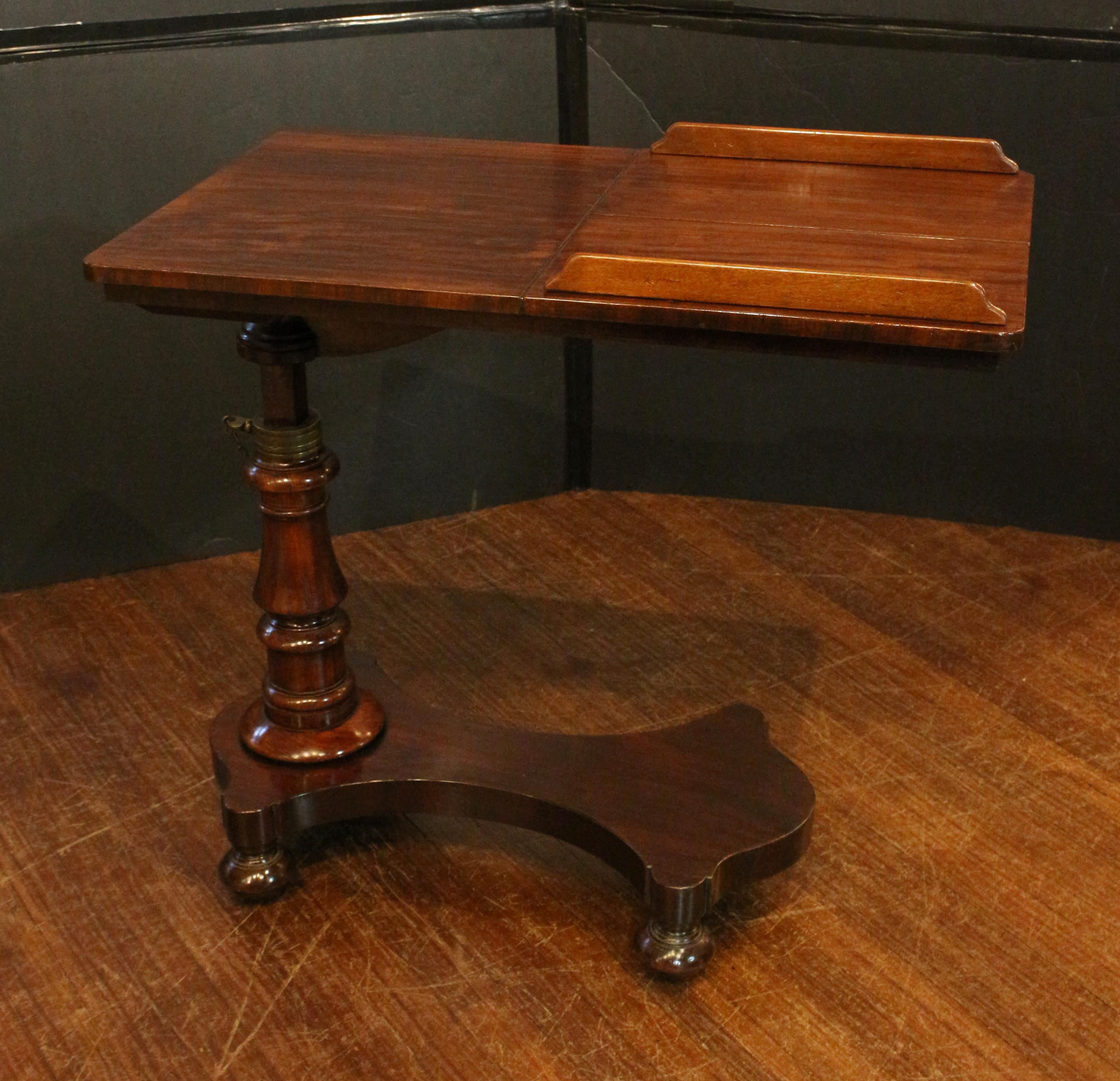 Circa 1860 adjustable height double sided reading table, English. Well figured mahogany. Nicely shaped base with four flattened bun feet. Bold turned column with brass collar and adjusting support & markers. Double sided adjustable angle reading