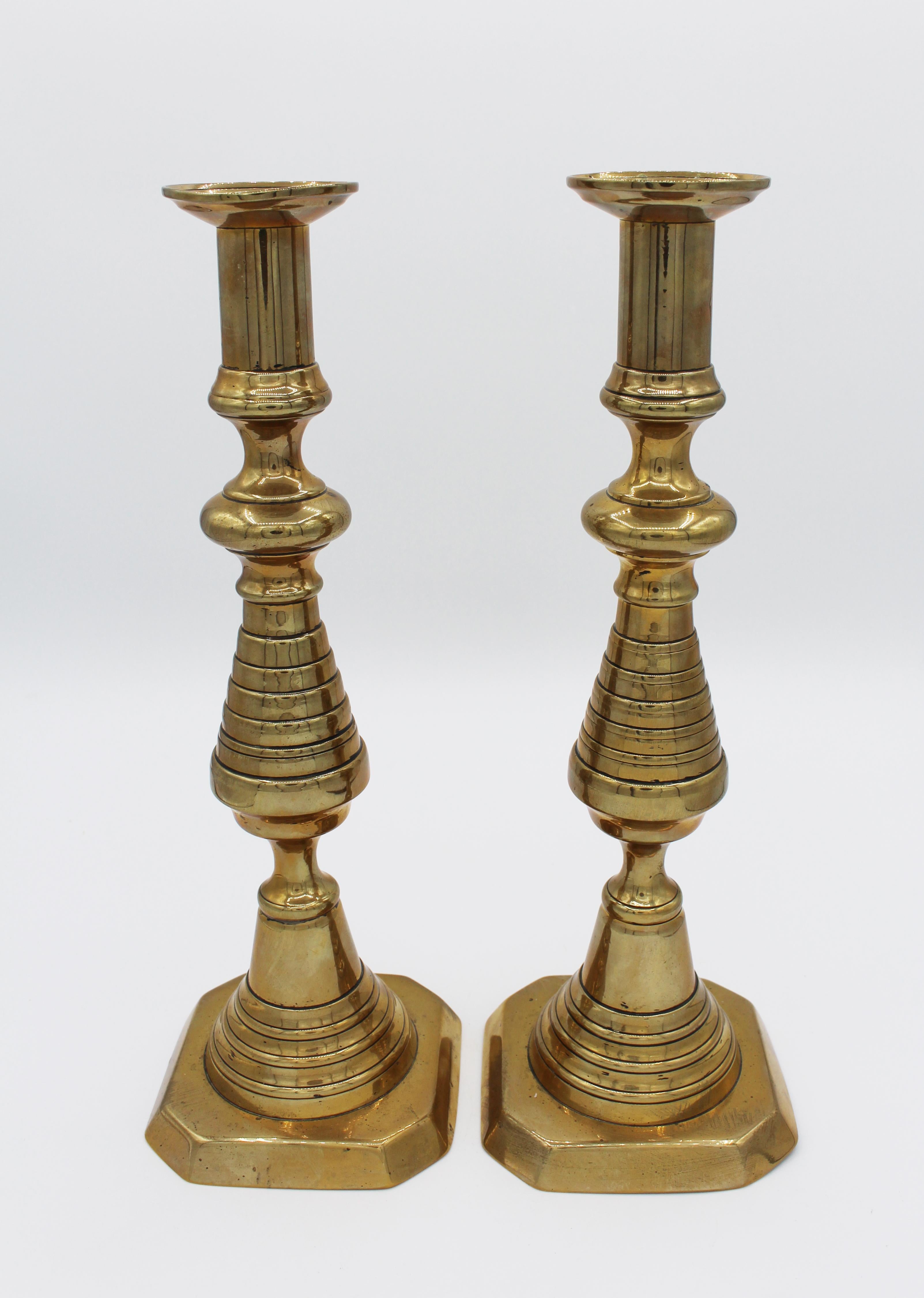 Une belle paire de chandeliers en laiton de grande taille et audacieuse, vers 1860, anglais. Forme de ruche classique en laiton inversé. Tous deux sont dotés de mécanismes de tige poussoir insérés dans la tige. Une base est légèrement usée.