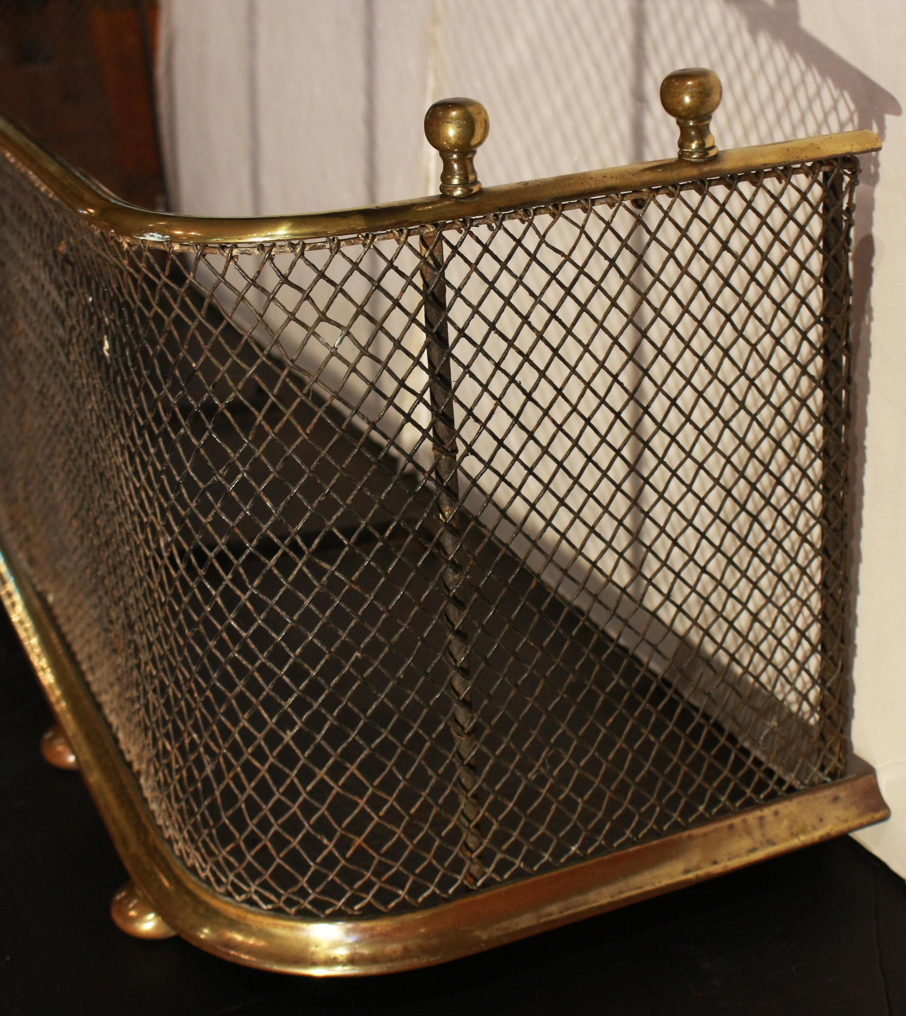Defensa de chimenea de latón y malla de alambre, inglesa, circa 1860. Protección integral de hierro para el hogar. La herramienta se apoya en los laterales y se detiene en la protección. Levantada sobre pies de bola bajo el borde de latón moldeado.