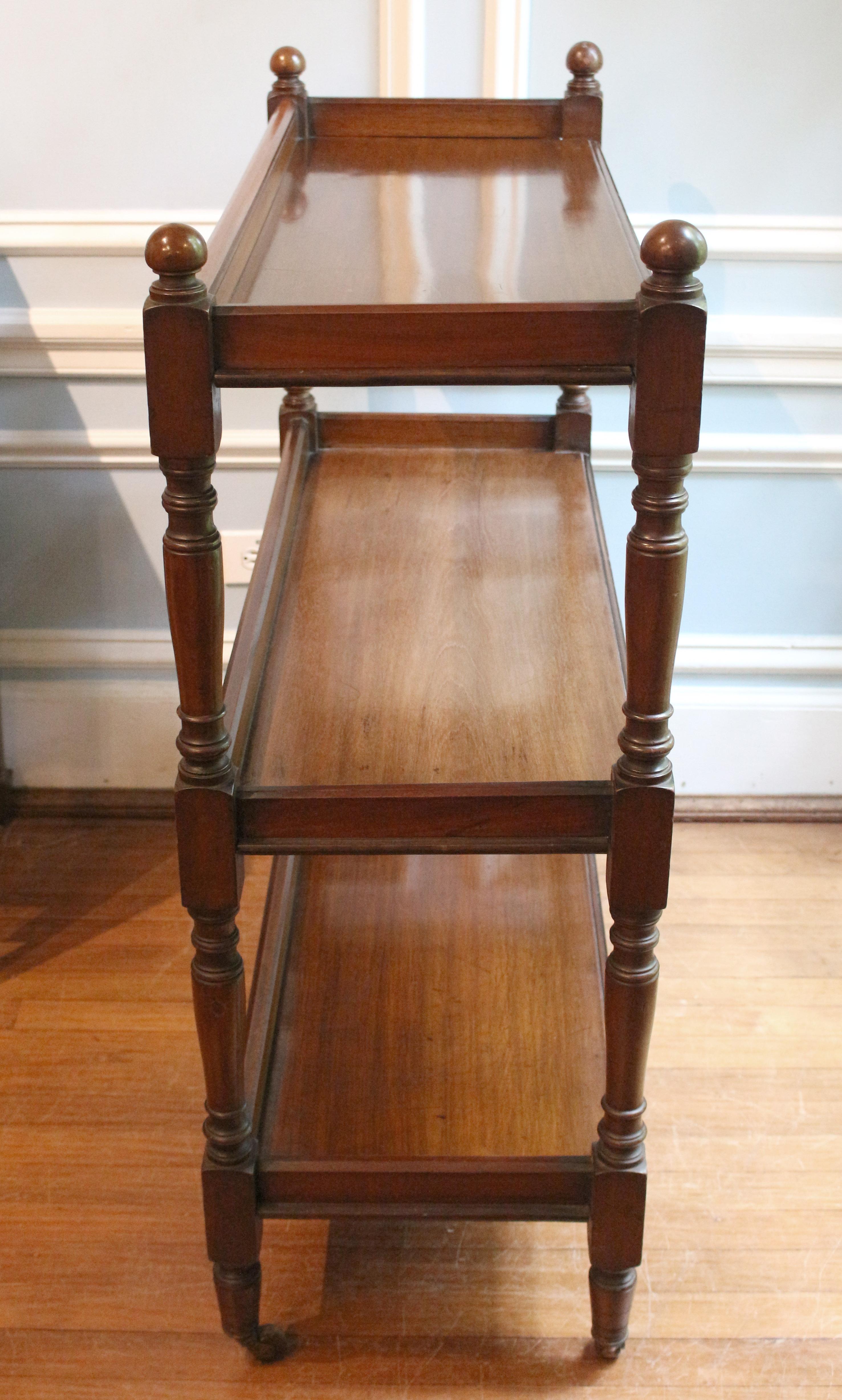 Circa 1860 butler's etagere buffet trolley or dumbwaiter, English. Solid mahogany. Well turned uprights with ball finials. Three tiers. Each shelf with gallery. Nice molded front edges. Original casters.
40.75