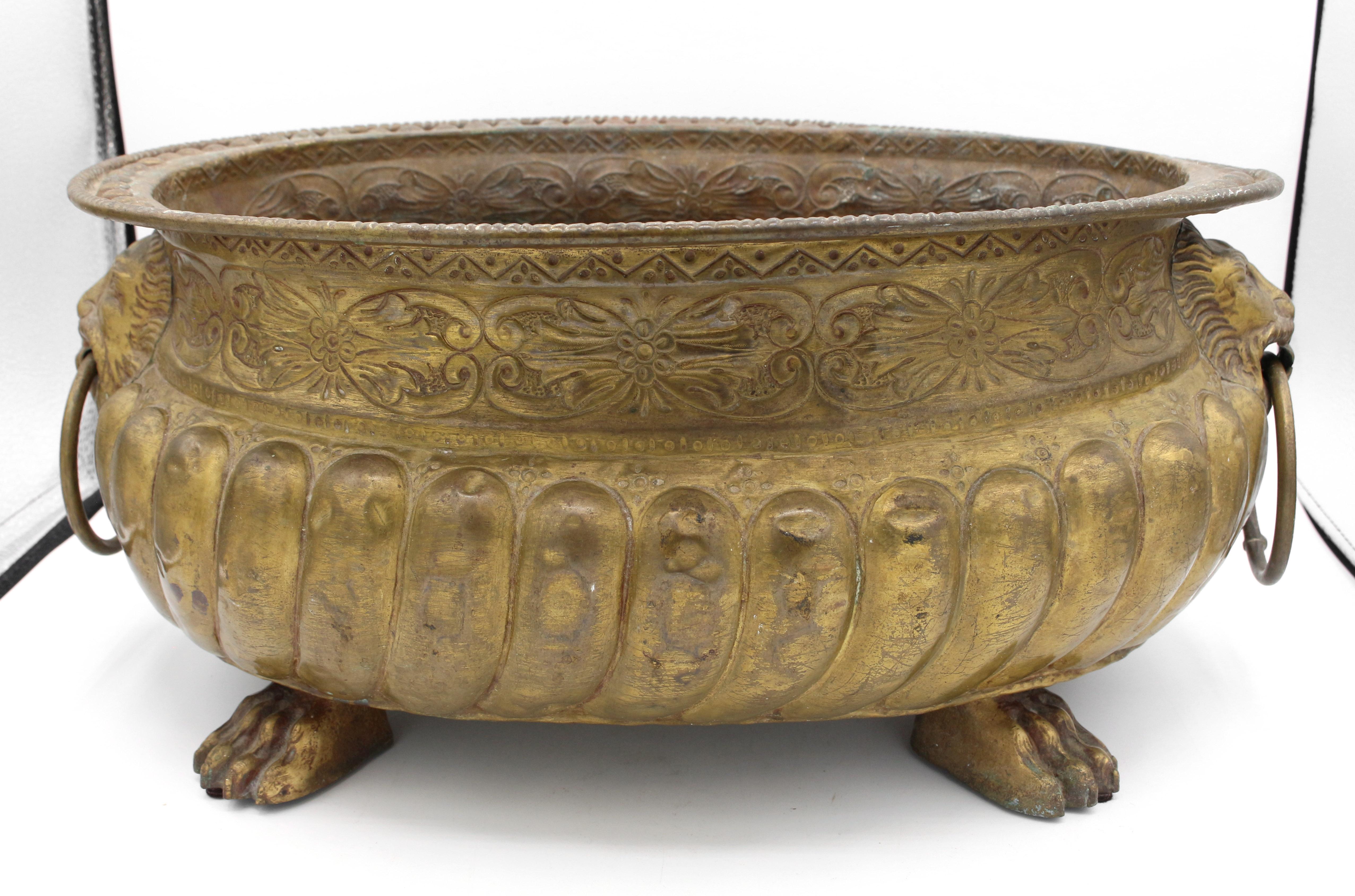 Circa 1860 brass oval jardiniere, French. Superb quality. Heavily gadrooned body surmounted by a frieze of florest & scrolls, lion mask ring turned handles, bold paw feet. Slightly bent rim at corner/edge.
16.5