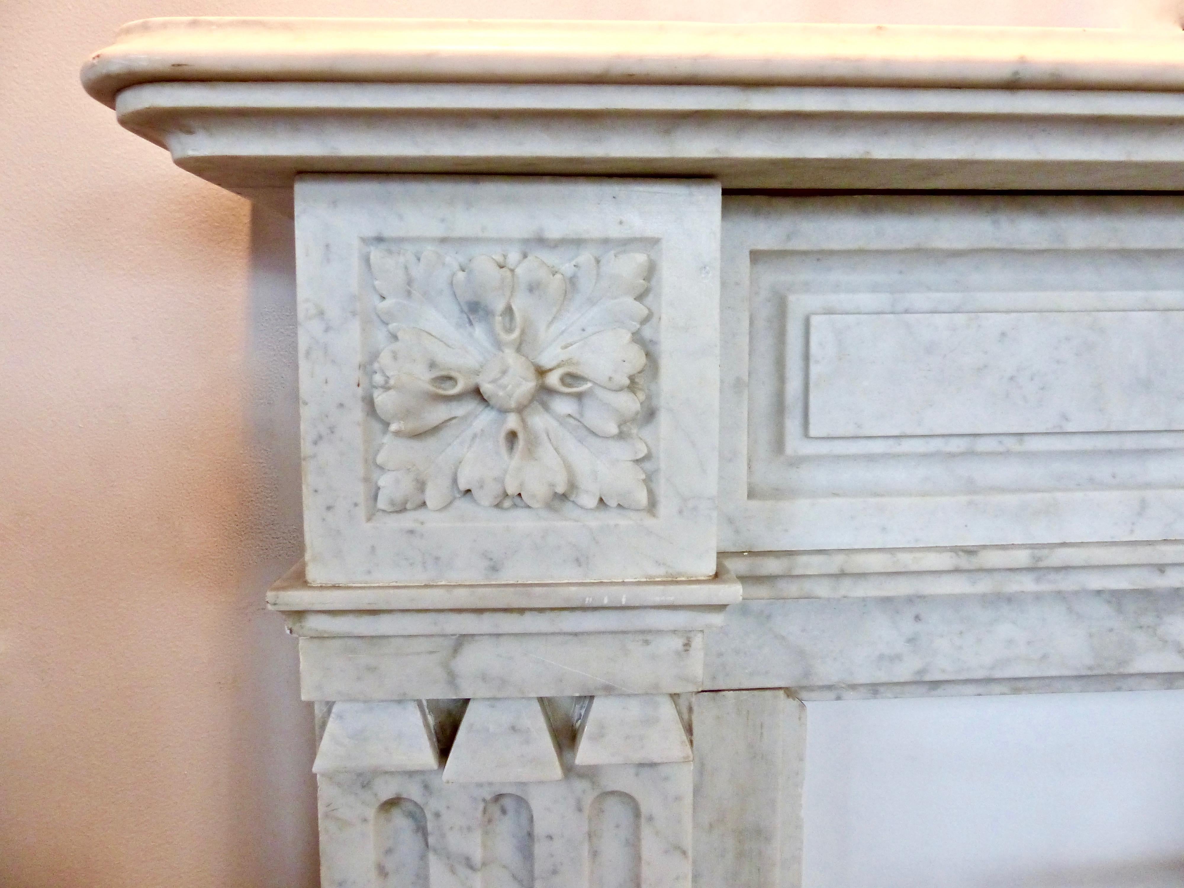 A French, handcrafted fireplace mantel/surround, circa 1860. Made from white Carrara marble with subtle decorative touches throughout, including unusual tiny scroll-work in its columns. Featuring a tiered top, with rounded edges, and a hand carved