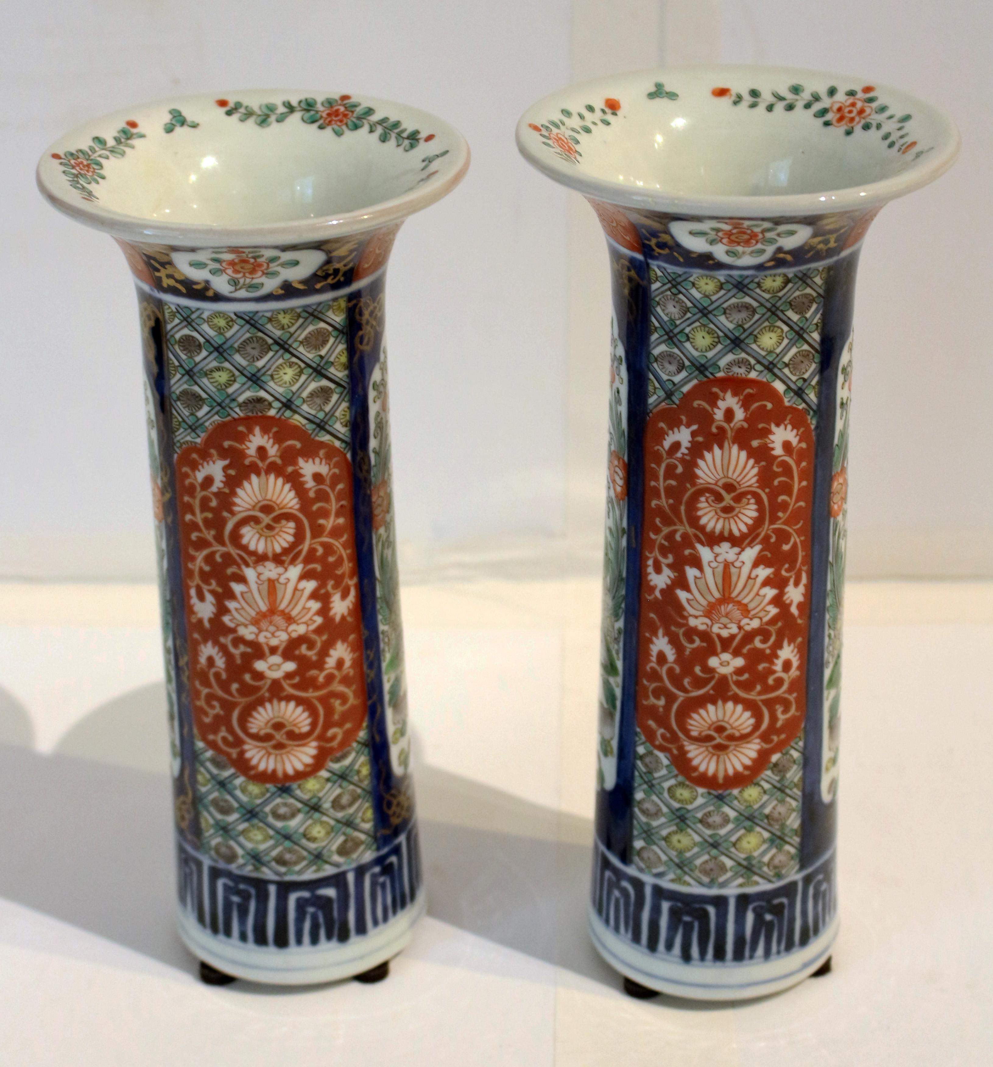 Circa 1860 pair of Imari vases, Japan. Beaker form; well decorated with trellises behind stylized burnt orange floral cartouches alternating with cartouches with a foo dog in a garden. One slightly shorter than the other. 4 1/4