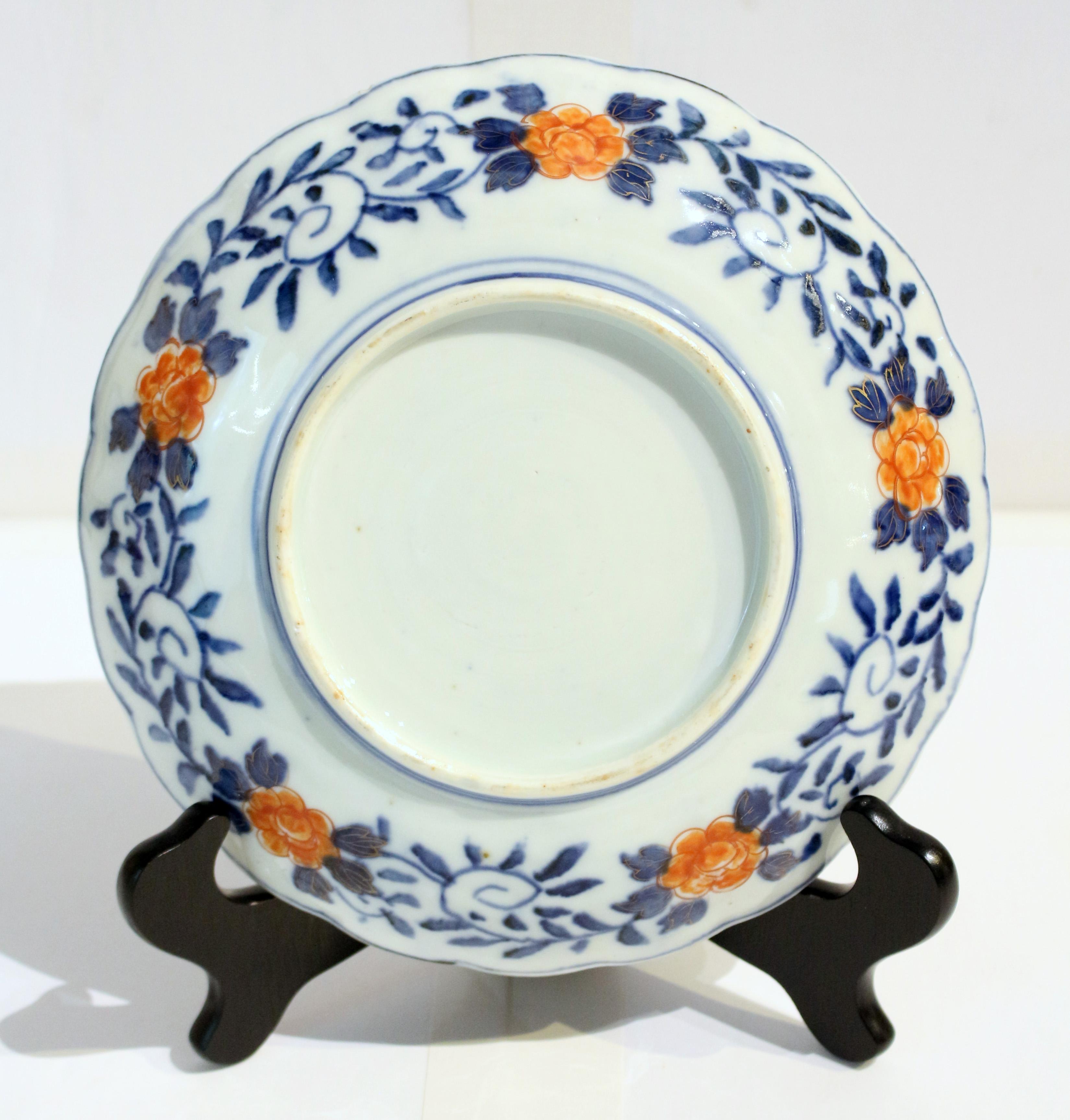 Circa 1860 scalloped Imari plate, Japan. Small chip under rim. Central medallion with vase of flowers with blue scalloped line surround. Border panels of alternating floral designs offset by cobalt, gilt & burnt orange cartouches. Well decorated