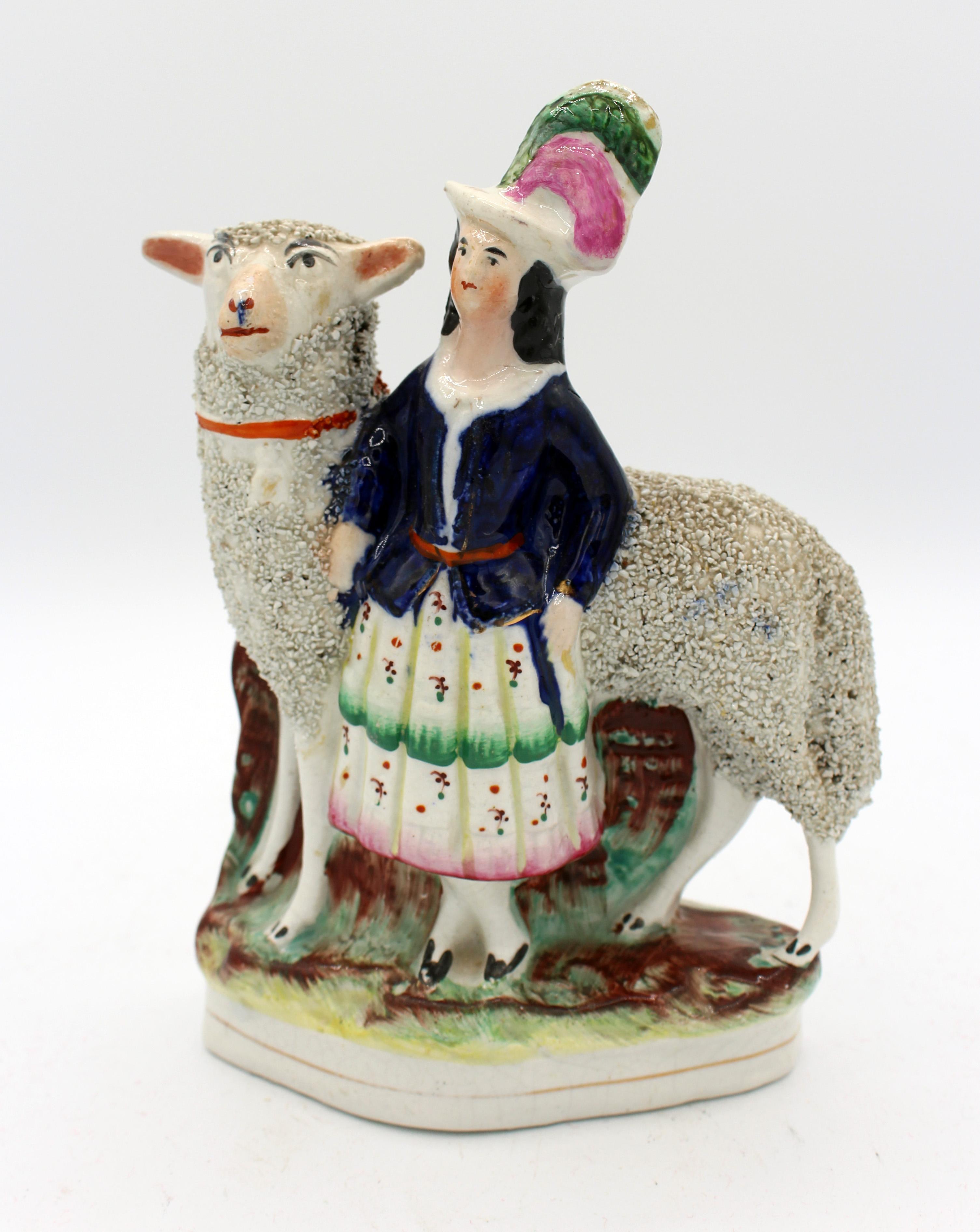 Staffordshire c.1860 figure of a Highland lass with sheep. England. Flat back; frit is used to achieve the woolly appearance. Old labels include repair history: restored sheep's ear and restuck head for lass. 7 5/8