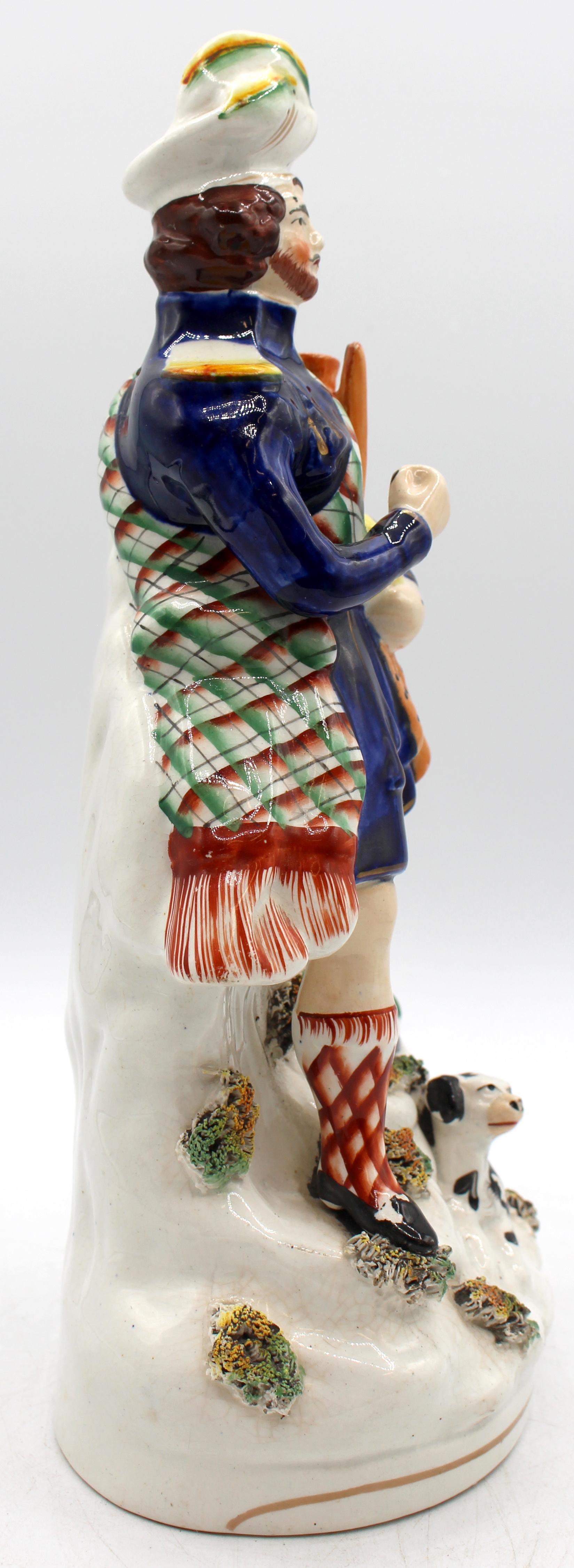 Circa 1860s English Staffordshire Highlander Figure. In full regalia repleat with hig bagpipes & black & white spaniel at his feet. Minor paint flecks, as expected. 11 1/8