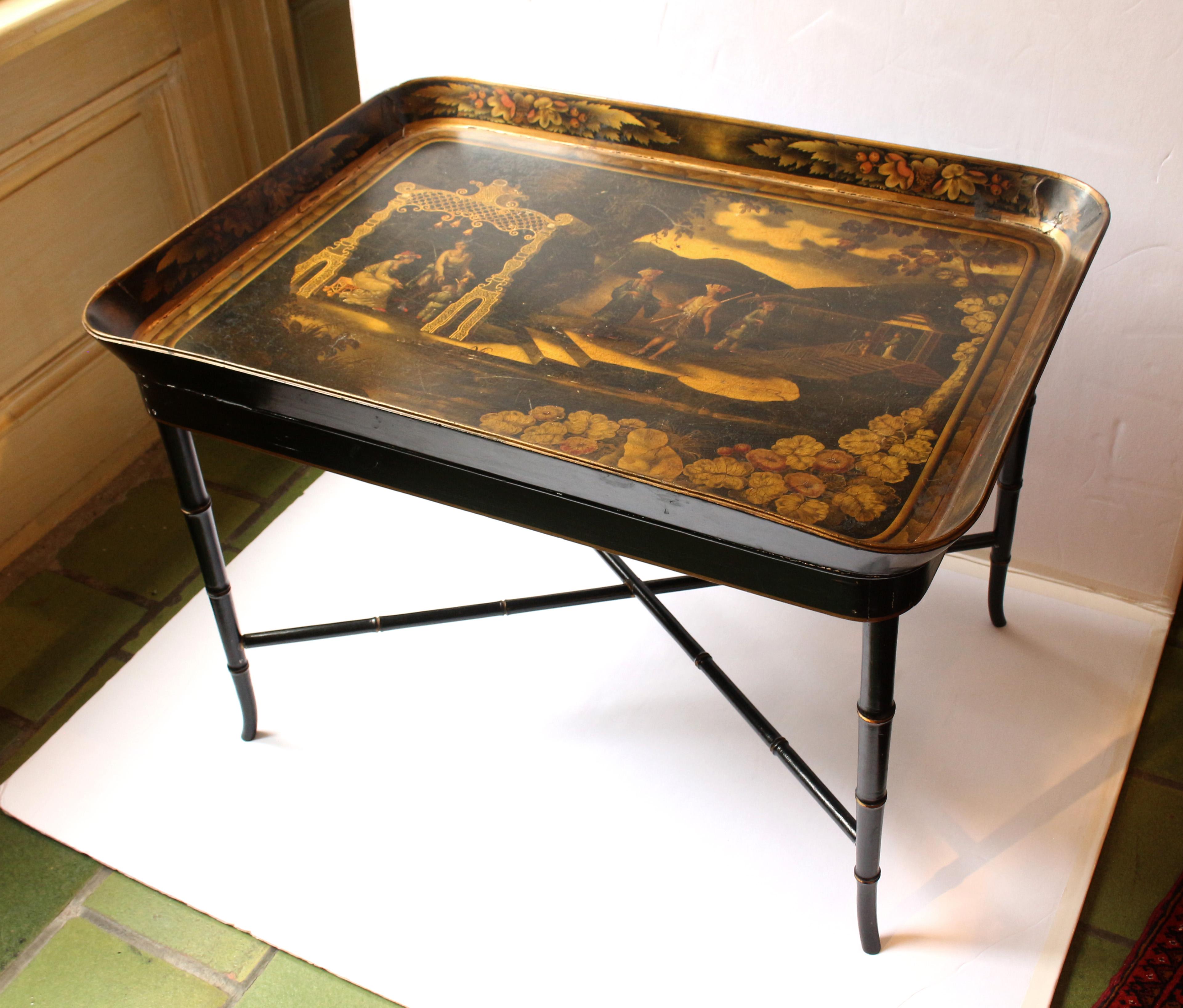 circa 1860s papier mache tray now with custom made coffee table stand, English. The tray with Asian influence scene of people at a lakeside pagoda with soft hills in the background and lush foliage in the fore. Gilt & green overtones. Typical corner