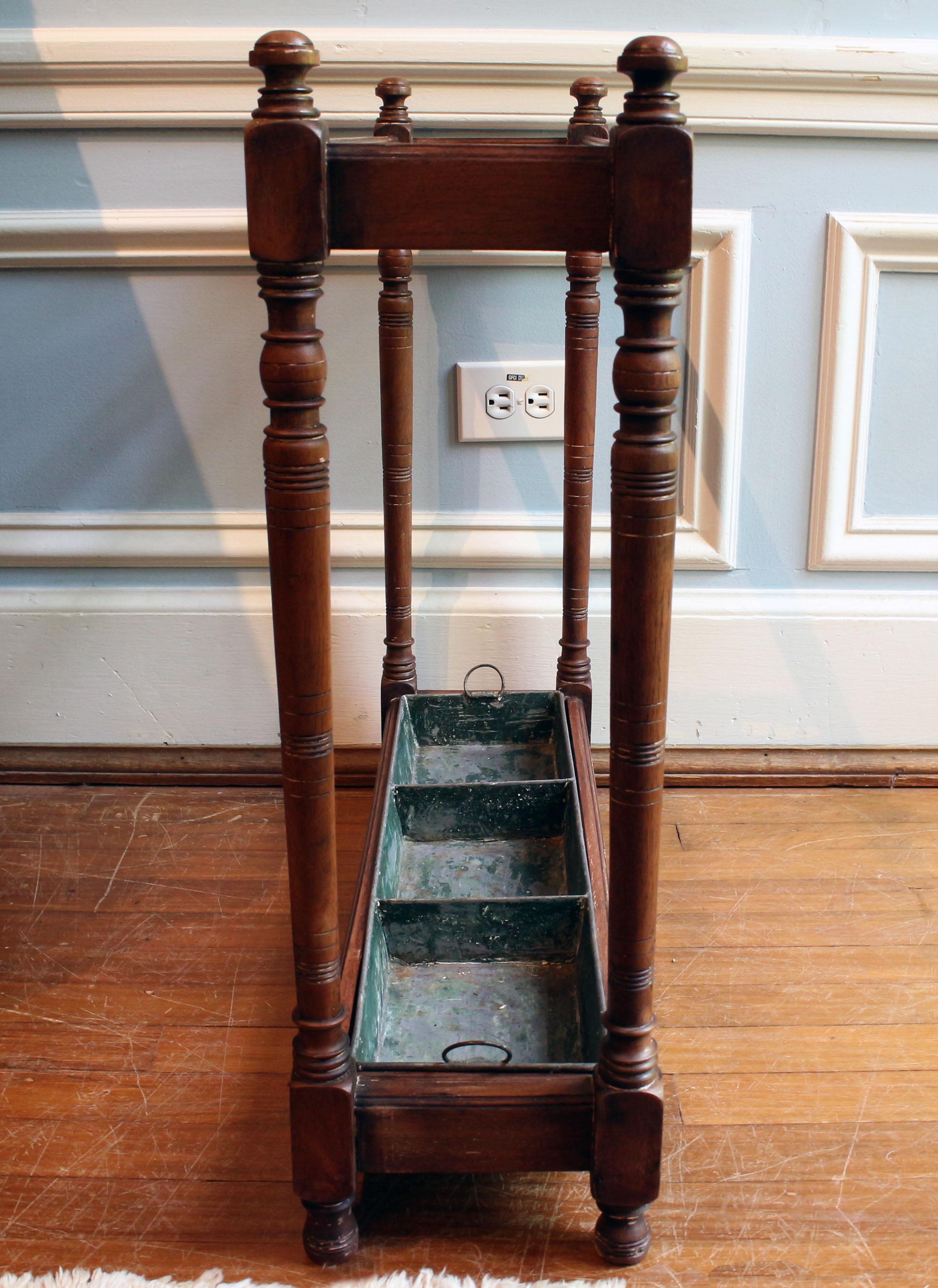 circa 1860s, Turned wood stick stand with drip tray. Wood with compartmented metal drip tray. Flattened ball finials atop columnar form ring carved uprights; molded rails. Expected wear given age & use in an English Country House, some old plaster &