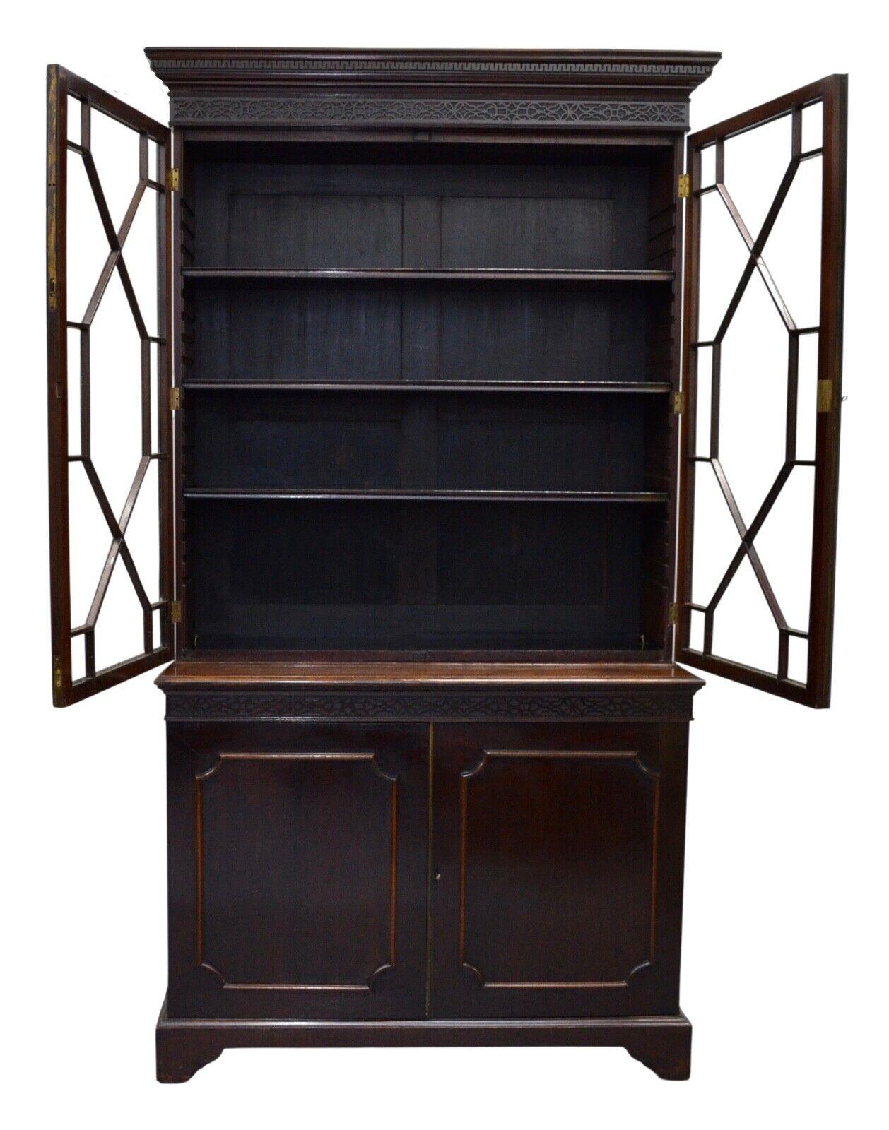 We are delighted to offer for sale this Chippendale revival english mahogany library  bookcase. It has an upper case carved molded edge cornice with detailed moldings and intricately carved fret work. The hinged glass door open revealing three