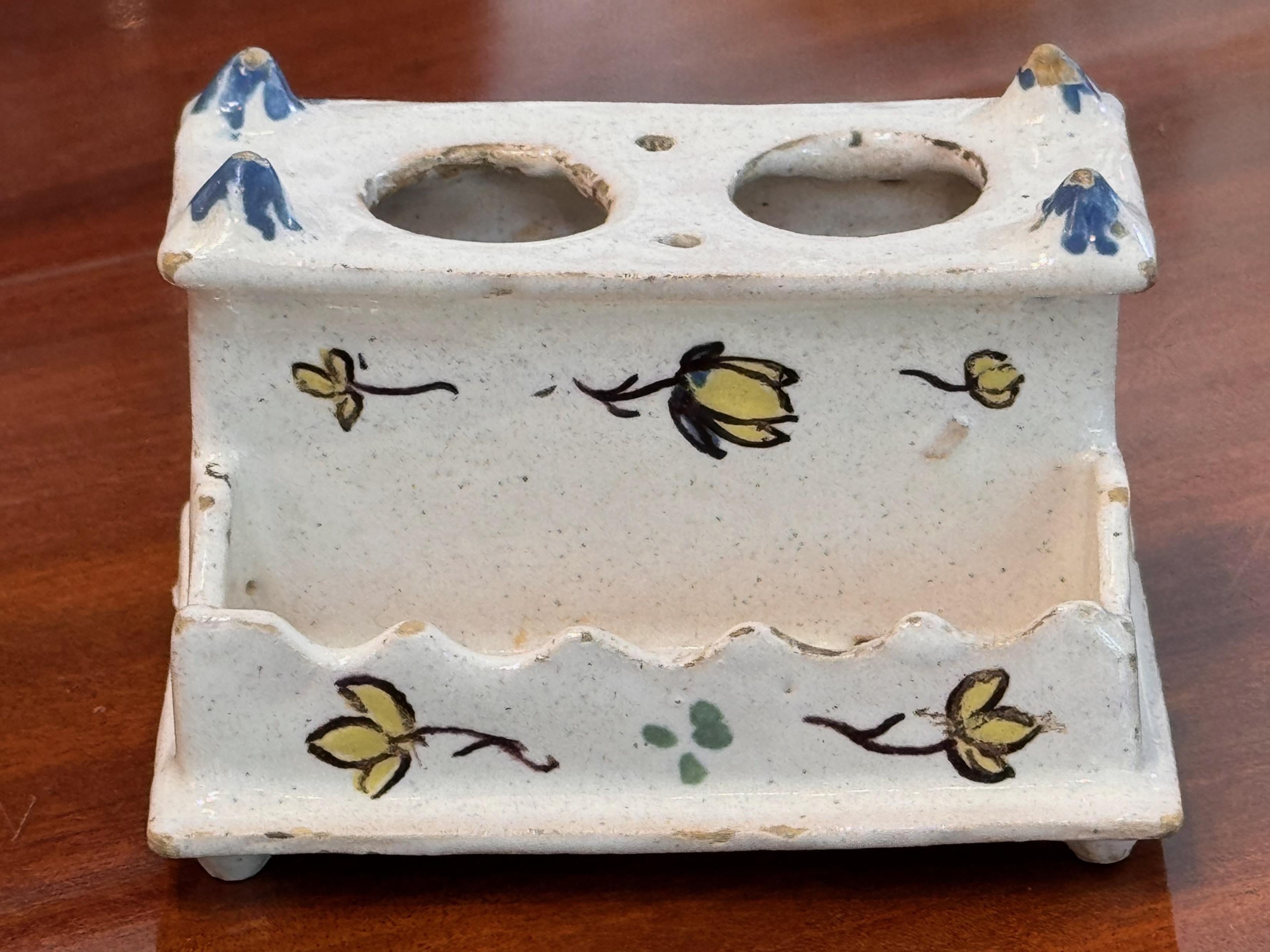 Charming 19th century Delft inkwell, hand-painted with stylized yellow blossoms and delicate green accents on a creamy glazed surface. The stepped design features two inkwell openings and a scalloped pen tray, with applied corner finials painted in