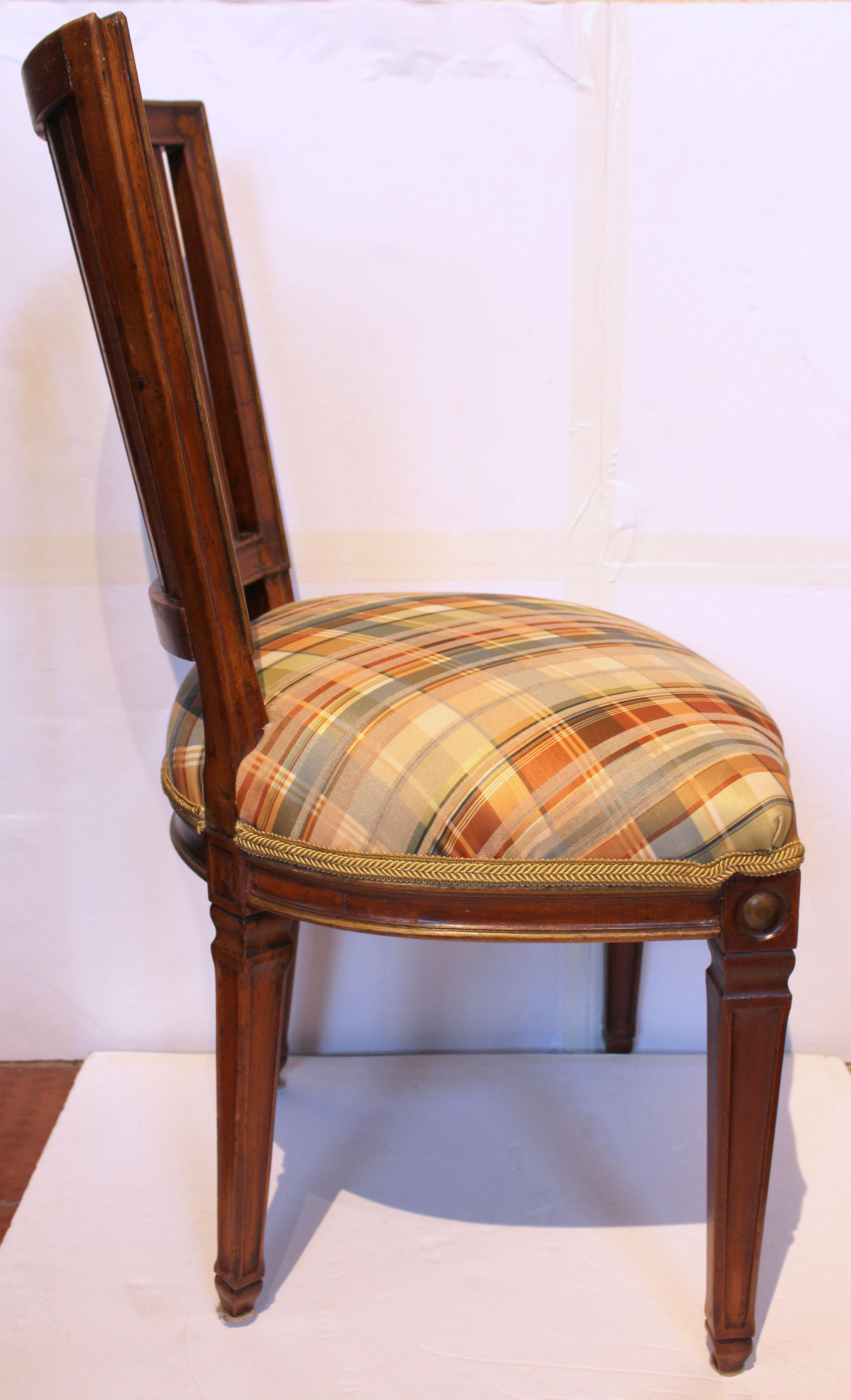 Sedia francese in stile Luigi XVI del 1870 circa. L'elegante struttura in noce modellato si riflette nel design delle gambe, dei grembiuli e dello schienale. Le cimase intagliate si ripetono dal coronamento al grembiule anteriore. Dettagli dorati.