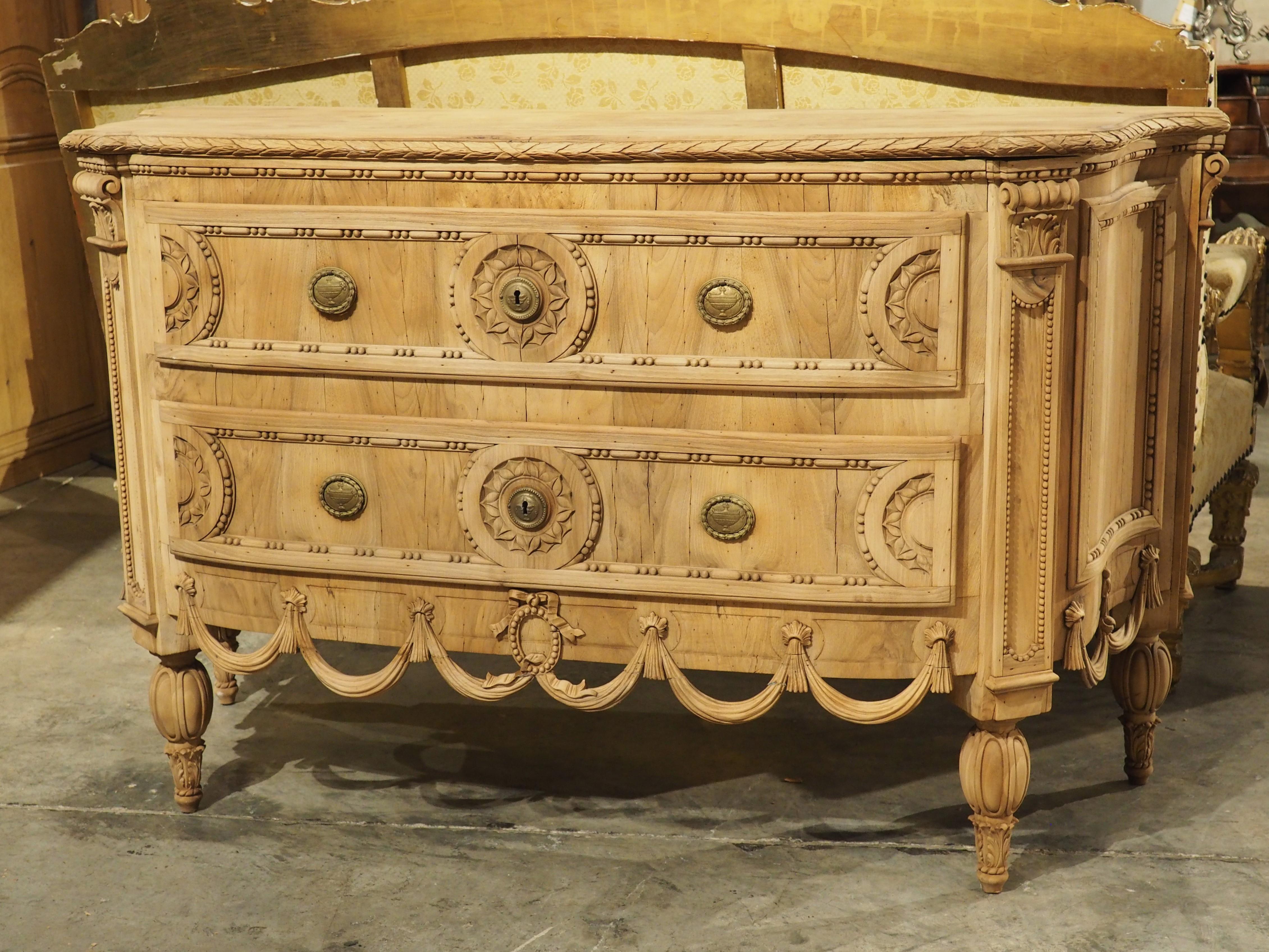 Hand-carved in the style of Louis XVI, this fantastic Italian walnut commode has a highly unusual form and dates to circa 1870. The two-tiered chest of drawers surmounts an unusual apron that is high off the ground and consists of a series of