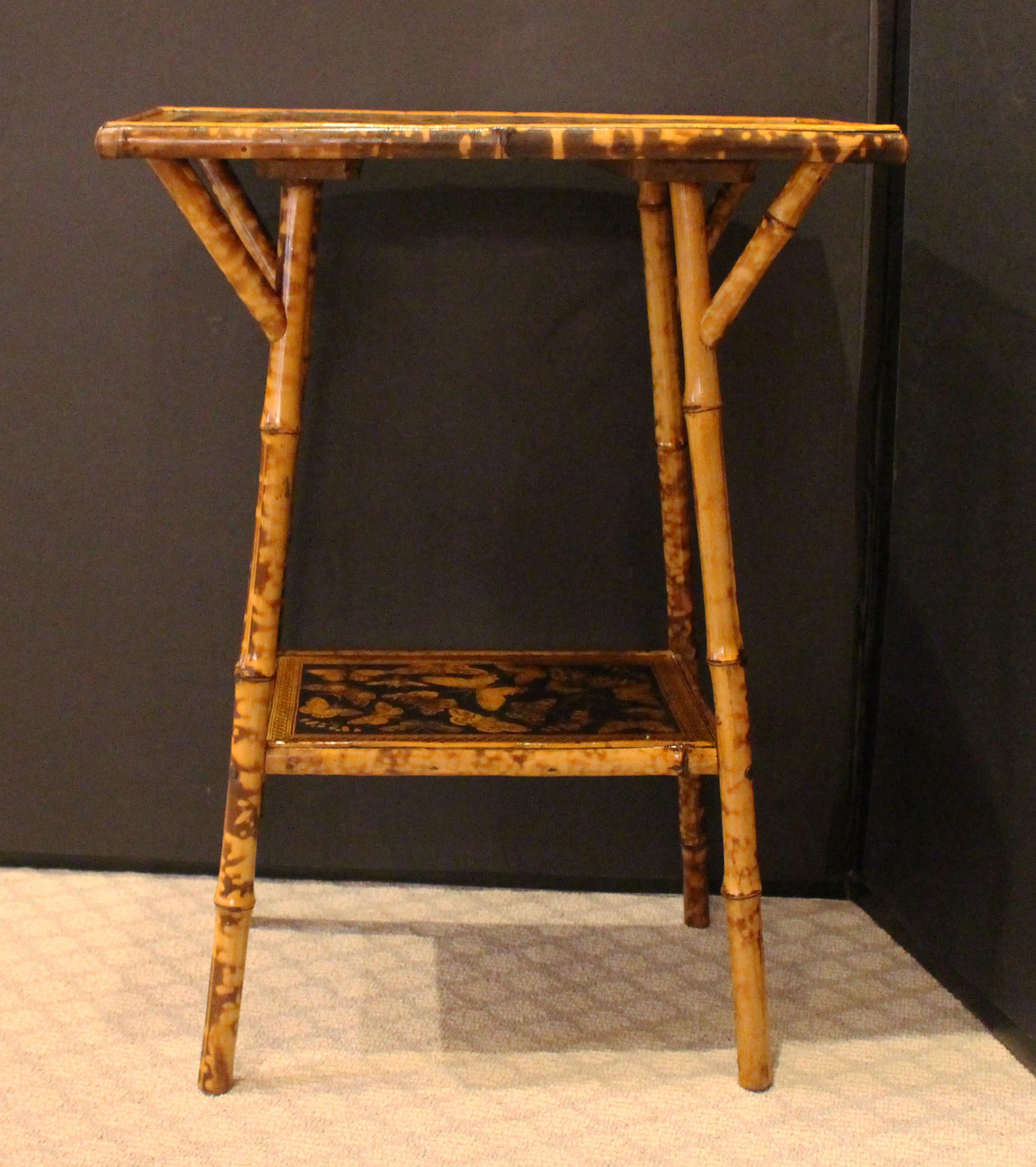 Circa 1870s two-tier rectangular bamboo side table, English. The surfaces now decoupaged with butterflies. Nicely figured bamboo with architectural struts supporting the top for interest and support.
19.25