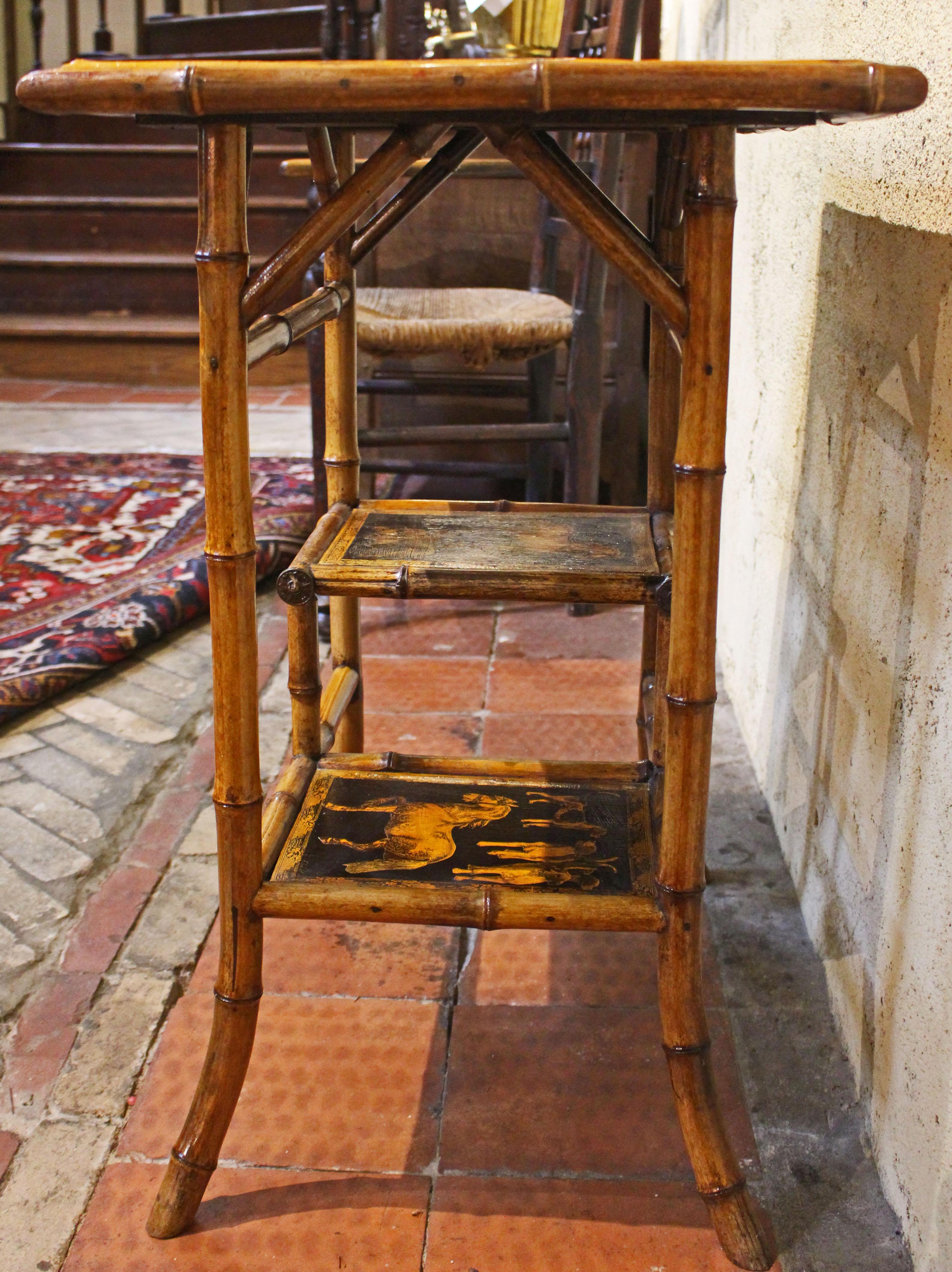 Circa 1870s Gran mesa rectangular inglesa de bambú de varios pisos. Las superficies originales ahora decoradas artesanalmente con perros y caballos. Los largueros y travesaños arquitectónicos de bambú añaden interés visual. Atractivo bambú de color