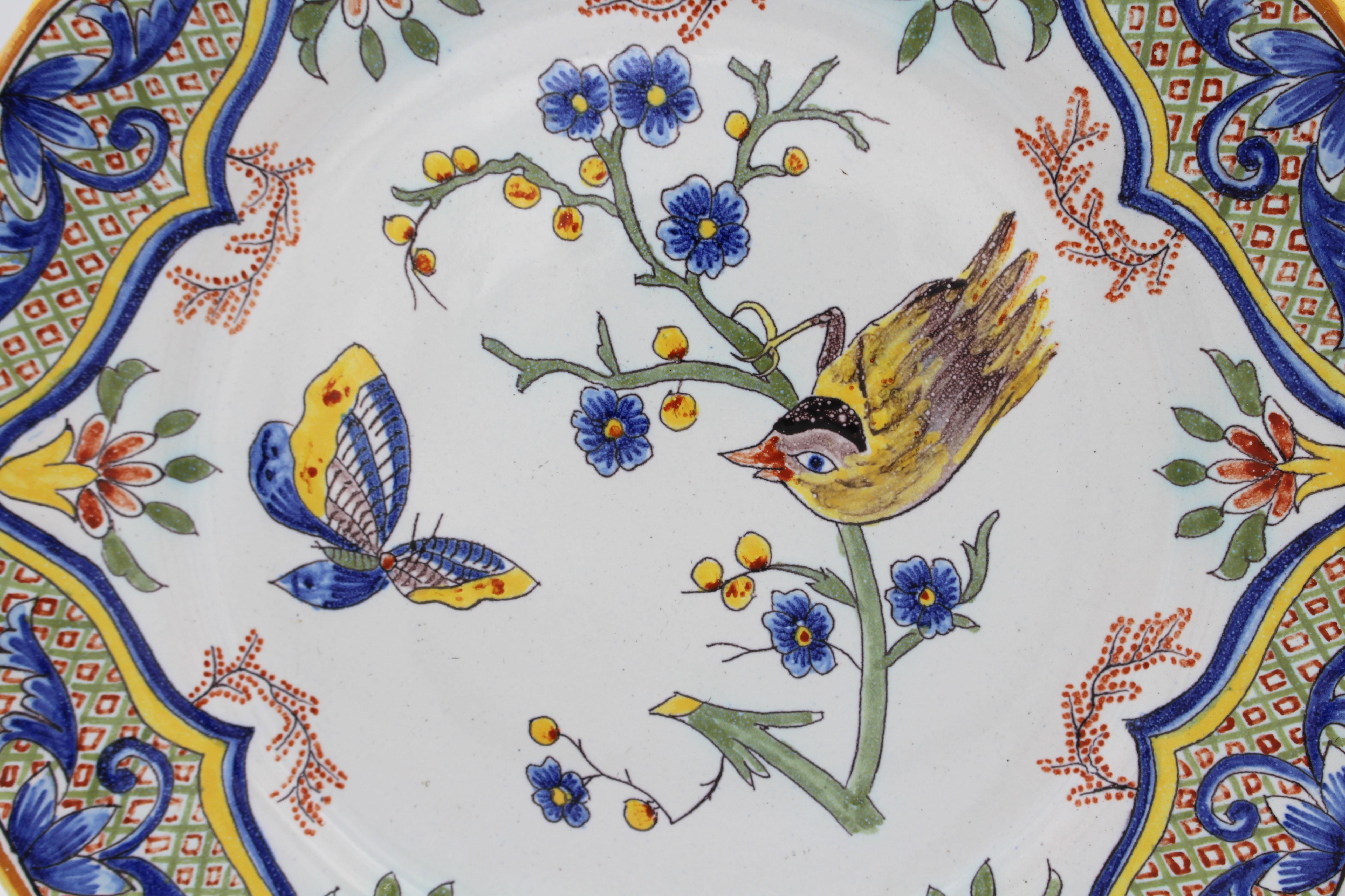 Vers 1870, assiette à bord festonné en faïence française. Charmant décor d'un oiseau sur une Branch observant un papillon, dans une forme et une bordure de style 18e siècle à diapason. Faïence française classique aux couleurs bleu et jaune avec des