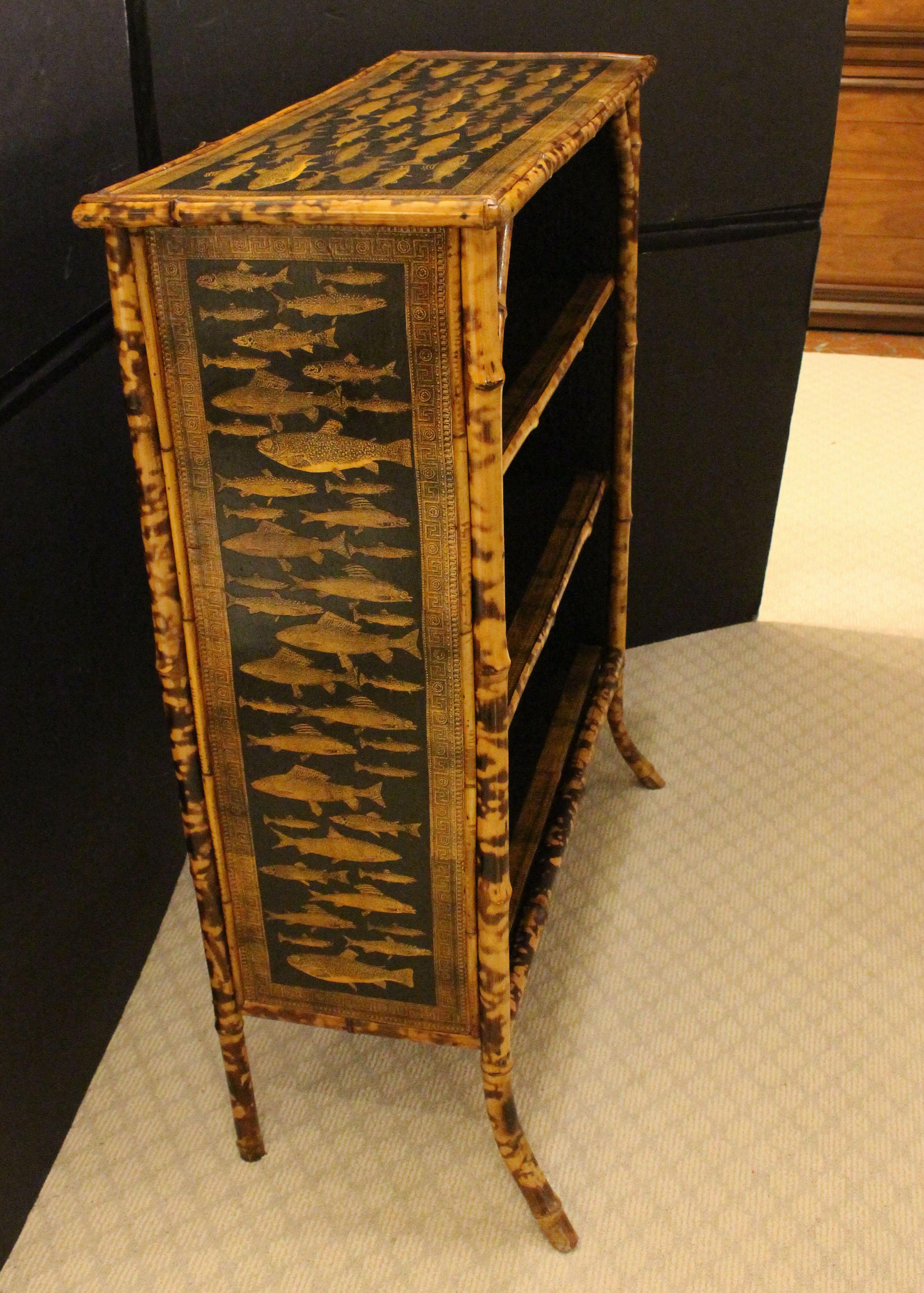 Circa 1880 bamboo bookcase now decoupaged with fish, English. The original rattan surfaces worn out and now replaced with custom hand-decoupage work of fish. Decoupaged Greek key borders on the three shelves. Architectural strut supports for top,