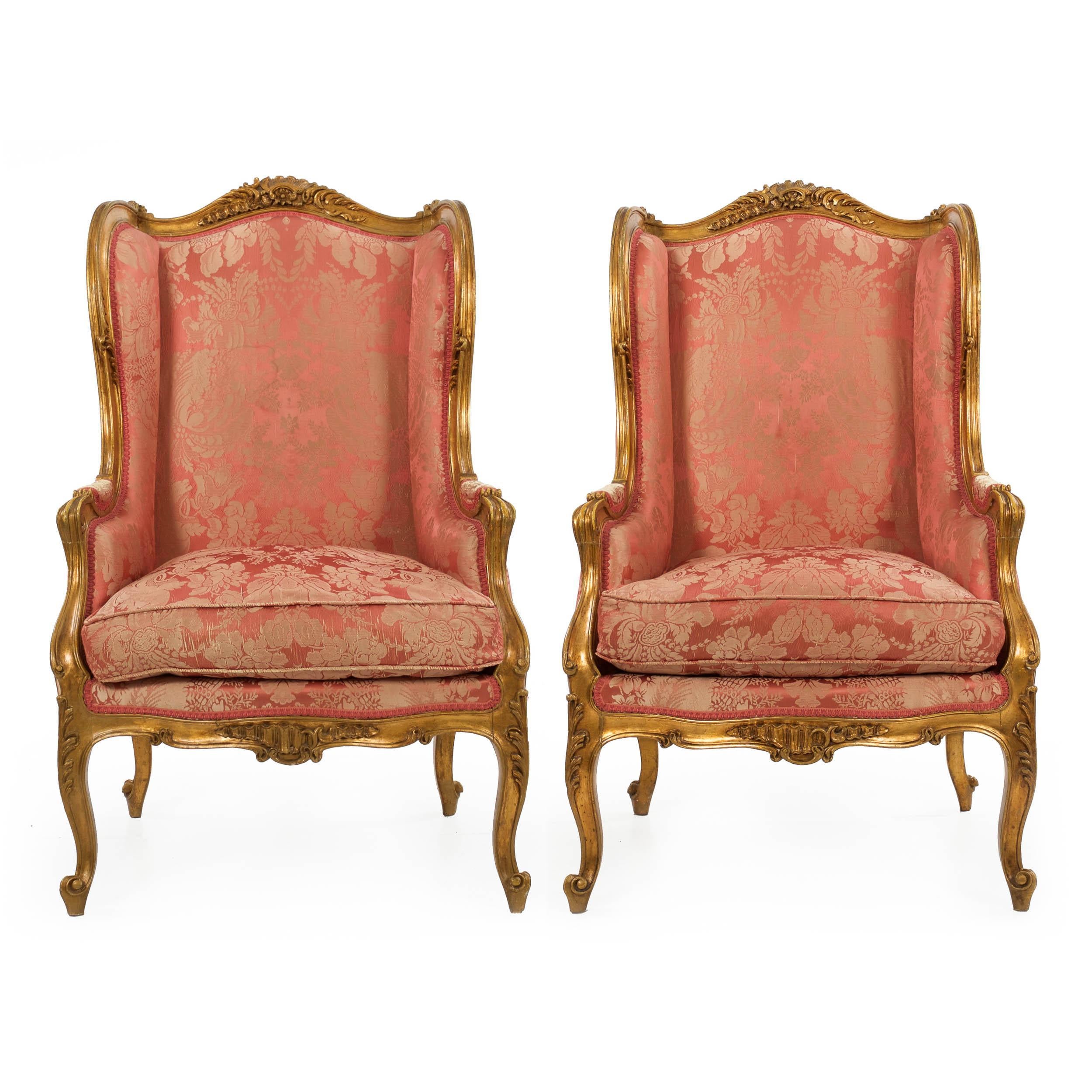 A gorgeous pair of French bergeres in the Louis XV taste, they were crafted circa the 1880s and exhibit crisp carvings inspired by the Rococo motifs of a century prior. The crest, apron and knees are most intricately embellished with integral