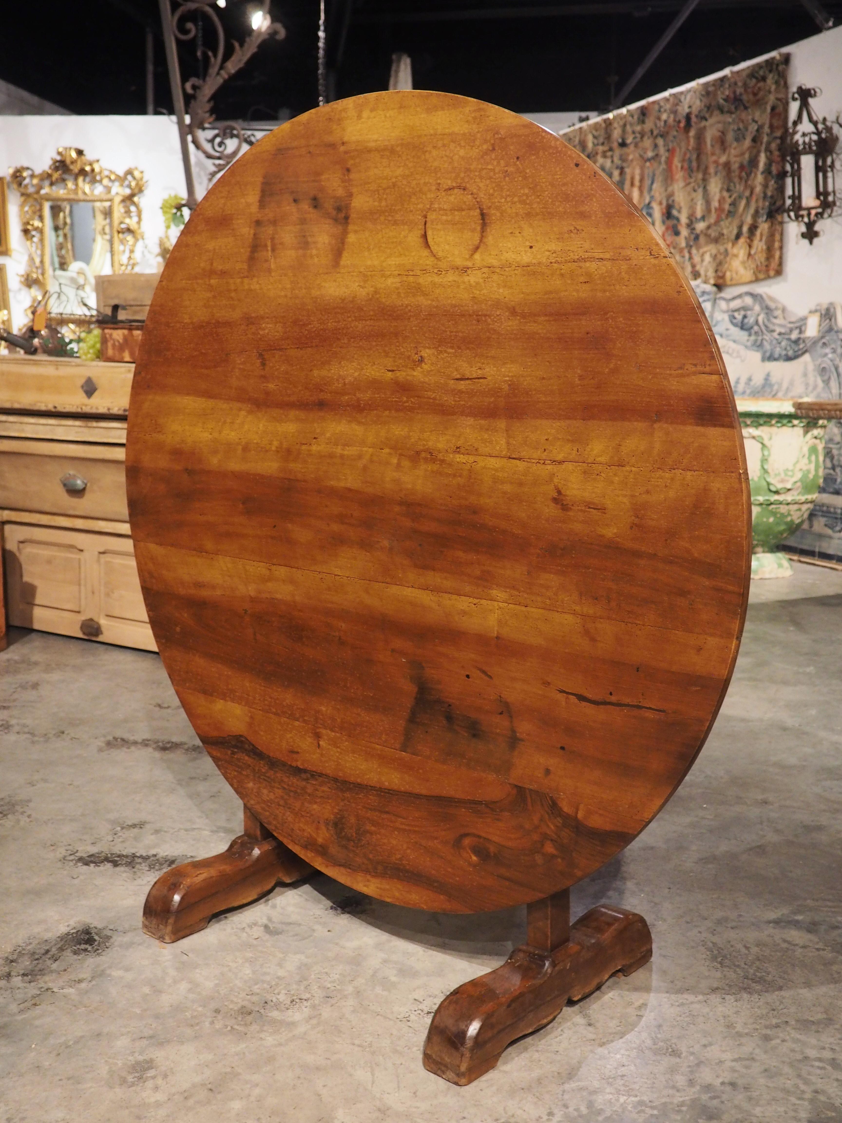 Hand-carved in walnut wood in France, circa 1880, this tilt-top table is known as a wine tasting or vintner’s table. The table features a striated top of brown and honey colored wood with some unique grains. Ideal for when space is at a premium, the