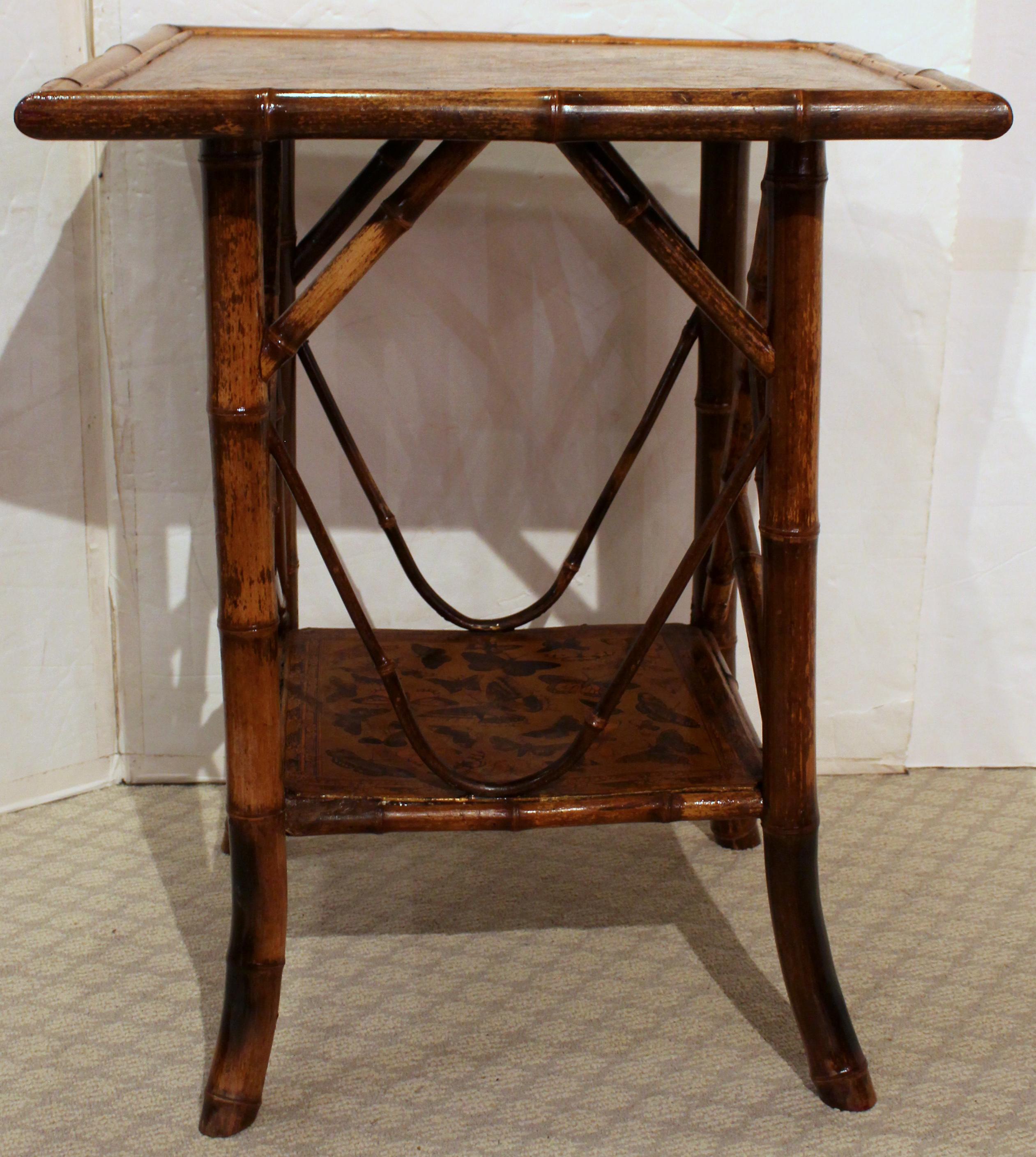 CIRCA 1880 großer 2-stöckiger quadratischer Bambustisch, englisch. Die Originaloberflächen sind jetzt mit bunten Schmetterlingen auf Goldgrund kunstvoll decoupiert. Die architektonischen und dekorativen Streben verleihen den Seiten des Entwurfs ein