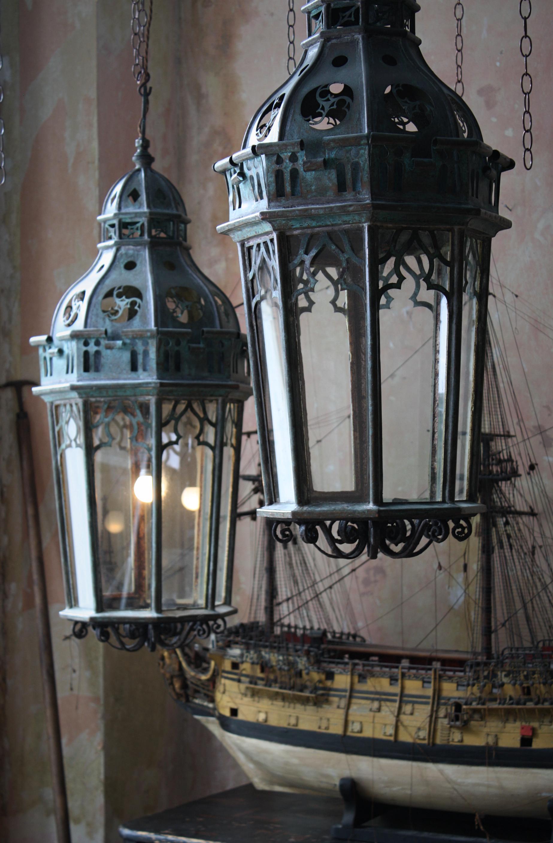 A substantial pair of copper and wrought iron gothic lanterns, likely to of been originally housed on exterior newel posts and later converted into interior hanging lanterns.

All glass sections are later replacements, the copper and iron work is