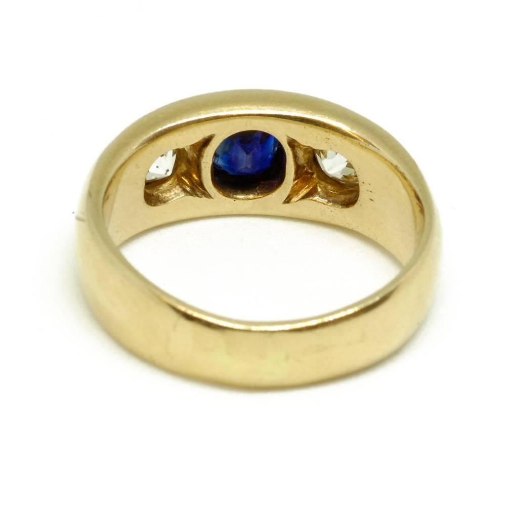 An 18ct yellow gold gypsy ring set with a sapphire flanked by two old cut diamonds. French, circa 1880.