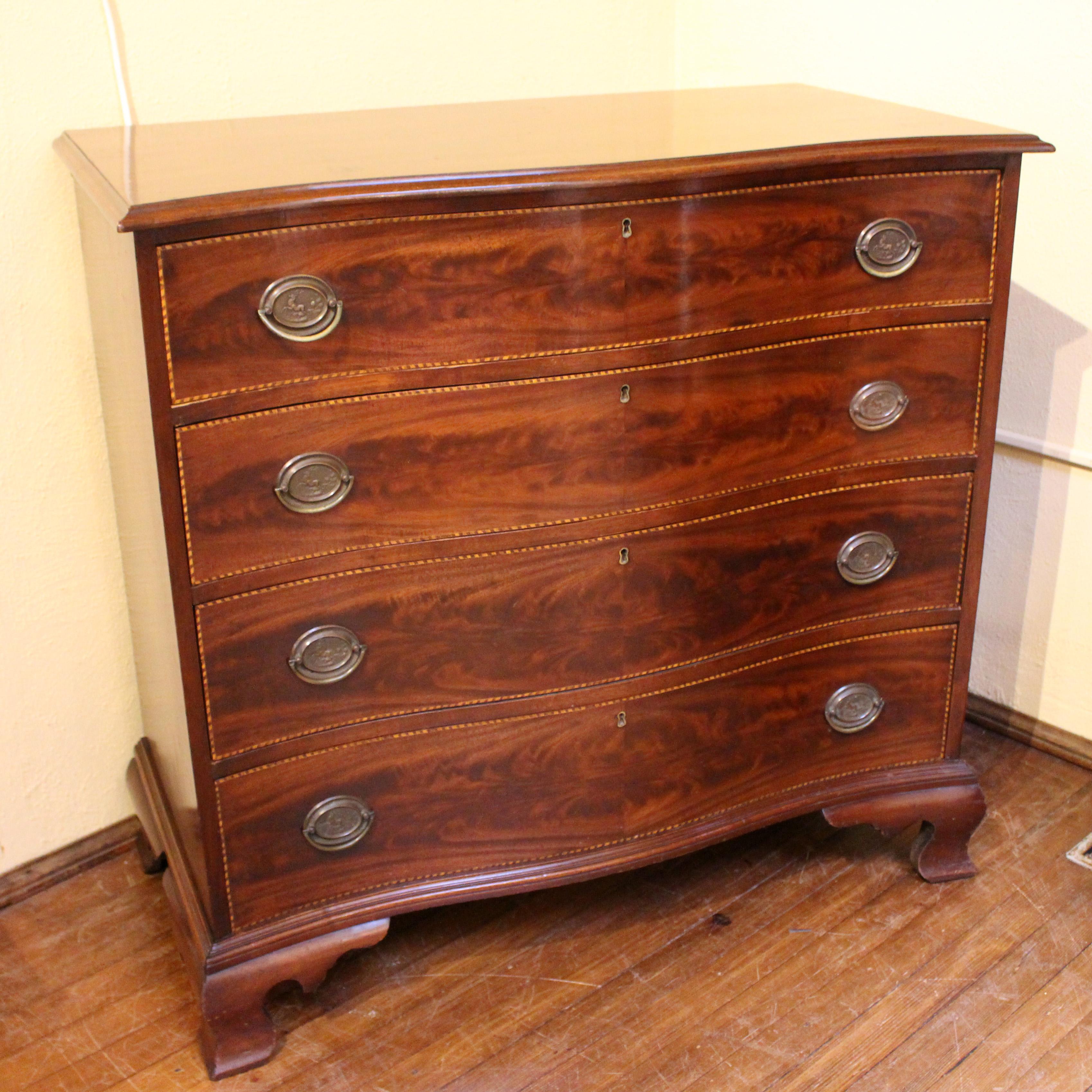 A fine c.1885-1915 bench-made Colonial Revival serpentine chest. American. Solid mahogany with flame veneer on the 4 graduated drawers and barber pole banding. Poplar secondary wood. Several re-built drawer runners.
Measures: 39 1/4