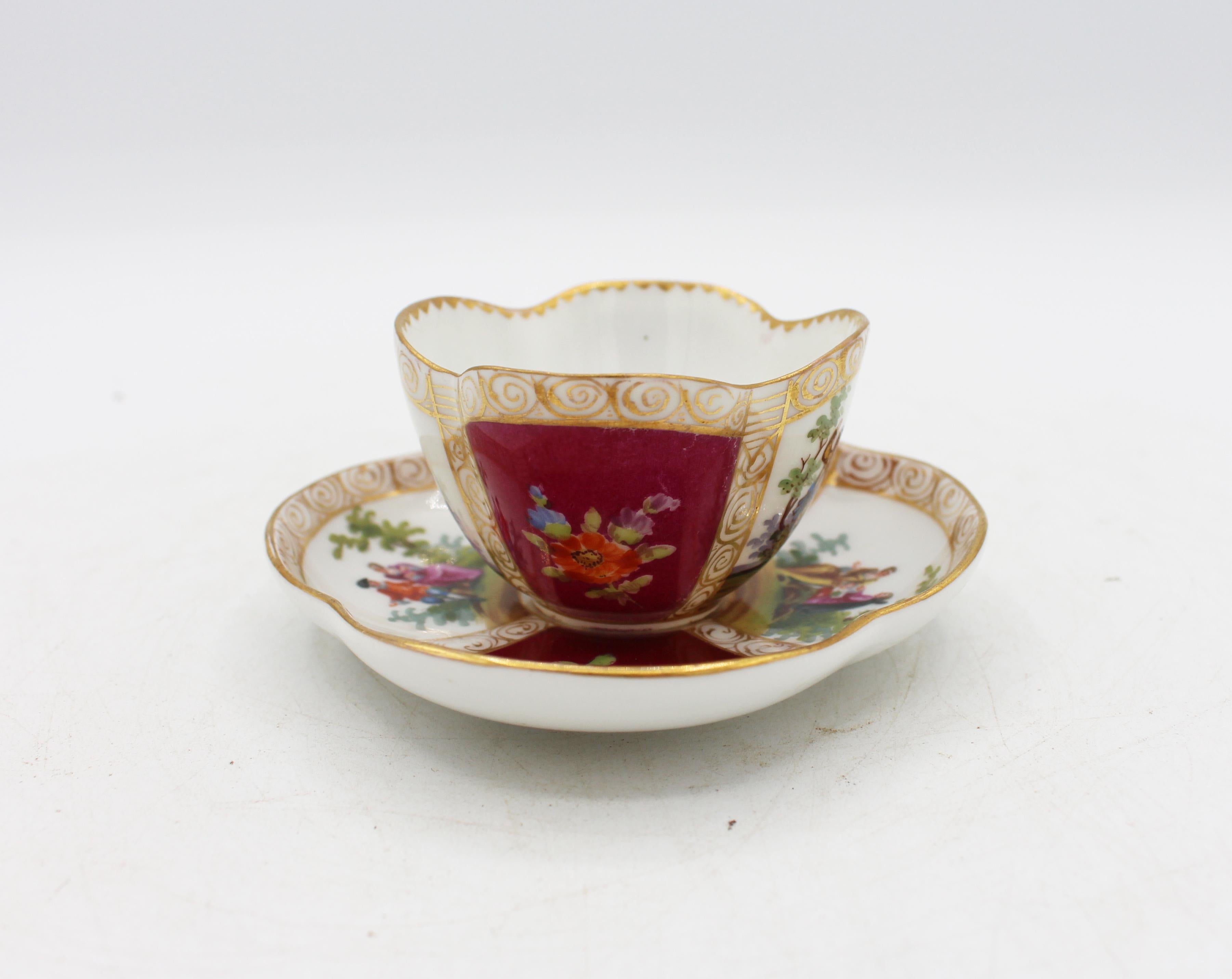 Circa 1888-1916 Richard Klemm, Dresden quatrefoil demitasse cup & saucer. Fully marked. Porcelain. Delicate scroll handle. Maroon ground with handpainted 