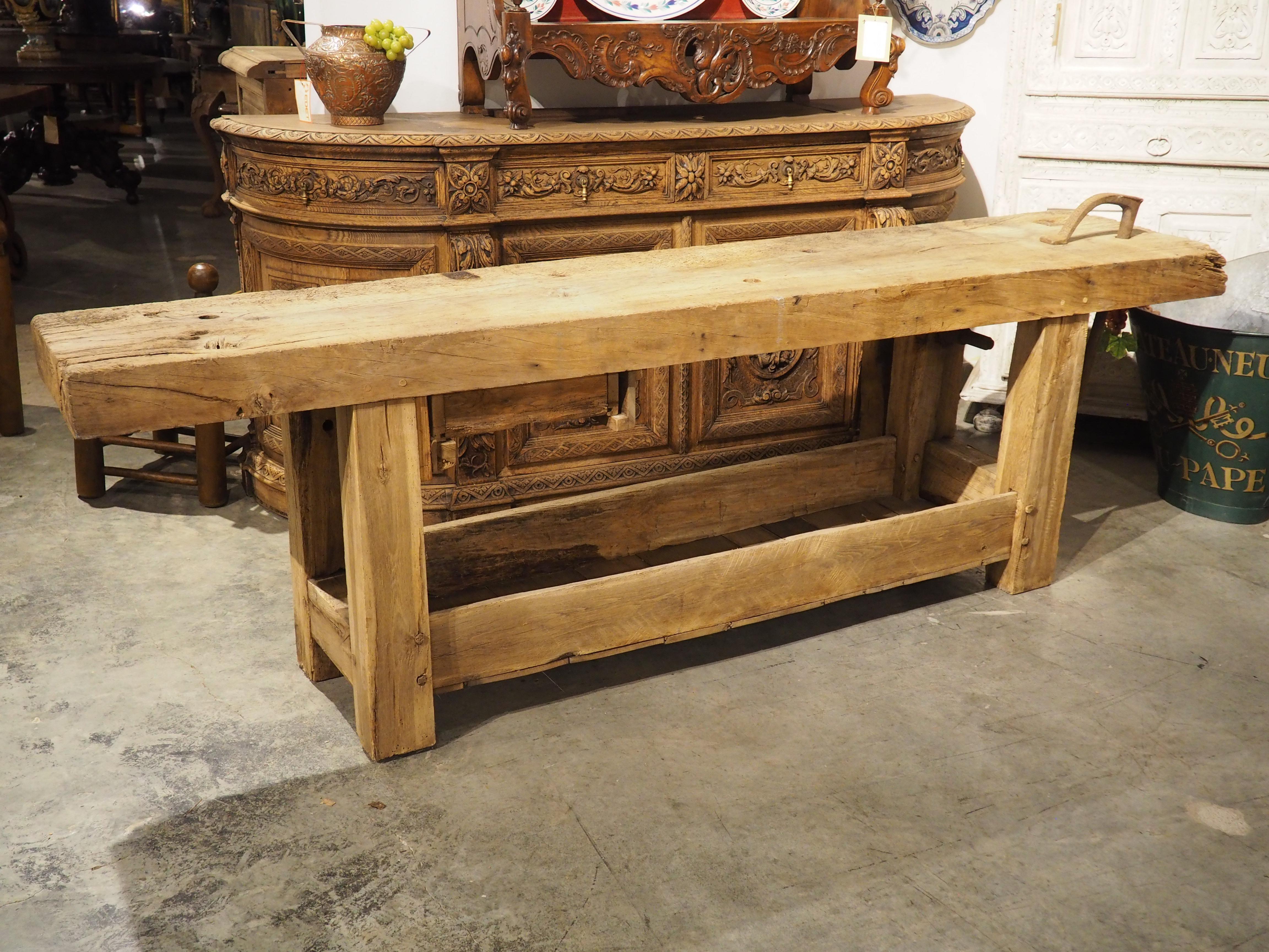 Originally the work bench for a French carpenter, this fantastic antique industrial table offers a storage shelf beneath, as well as a small drawer under the four-inch thick top. Hand-carved circa 1890, the wood has been bleached more recently