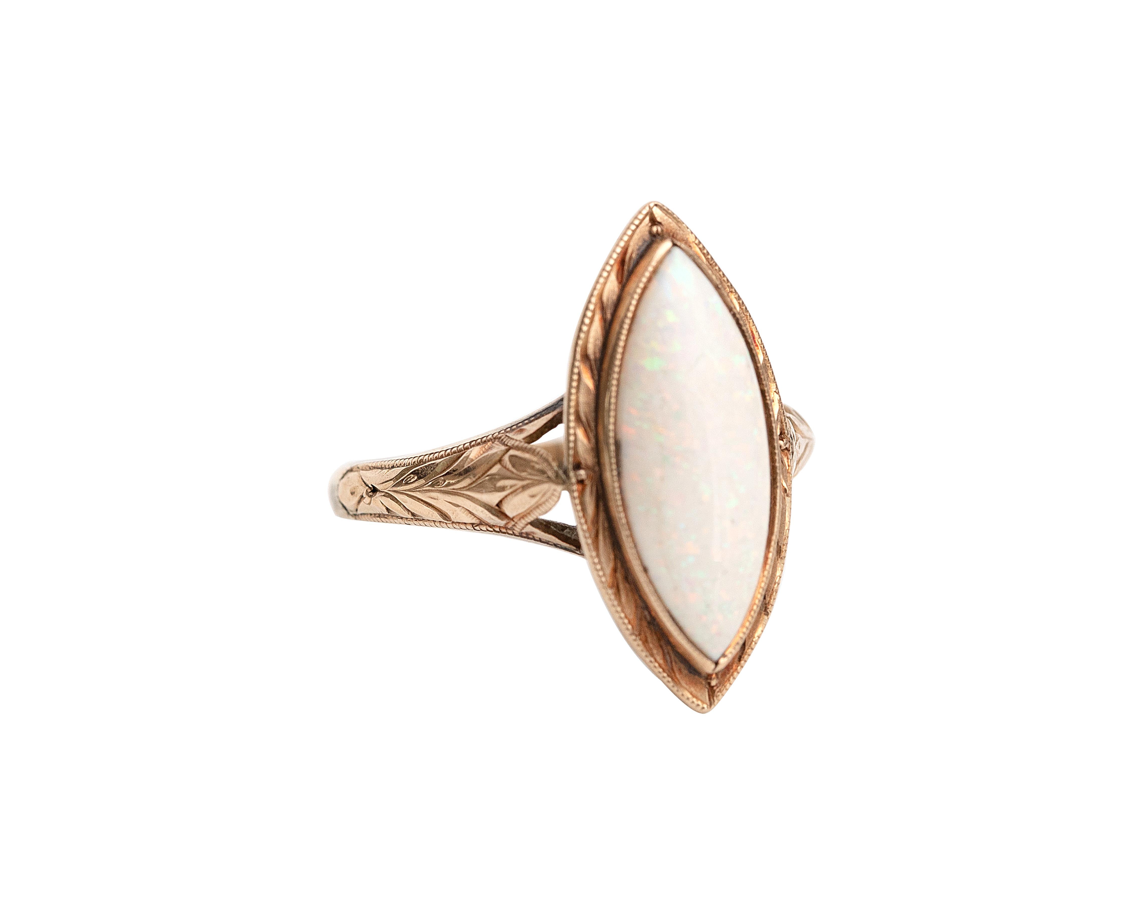 Here we have an excellent example of a Victorian-era 18K yellow gold ring with a large opal solitaire. The marquise cut center opal is flanked by intricate engraved shoulders as well as a matching etched design around the rim. The center opal is