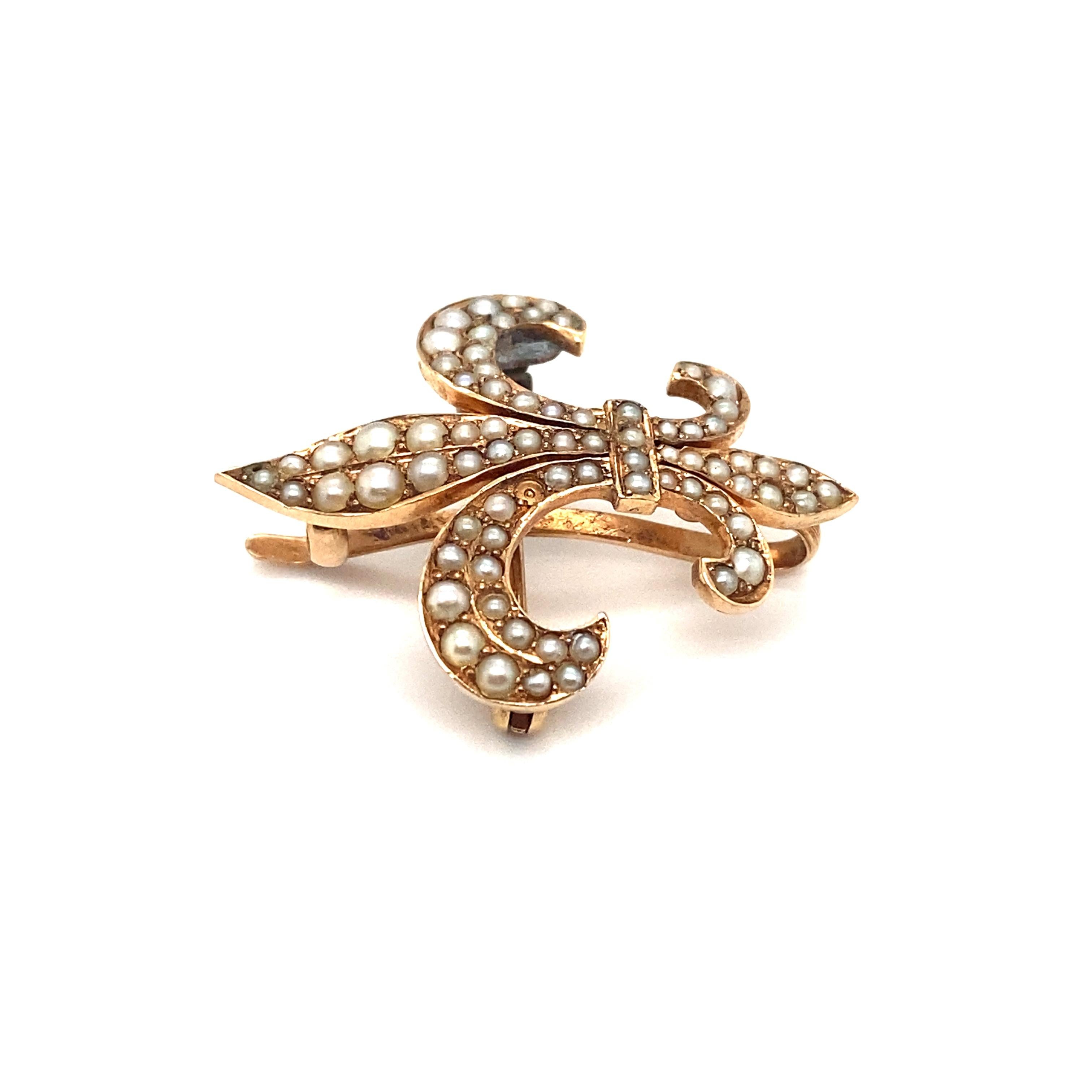 Item Details: This antique brooch is made in France and has a fleur de lis design with seed pearls. 

Circa: 1890s
Metal Type: 14 Karat Yellow Gold with Silver Accents
Weight: 4.6 grams
Size: 1.2 inch length x 1 inch width