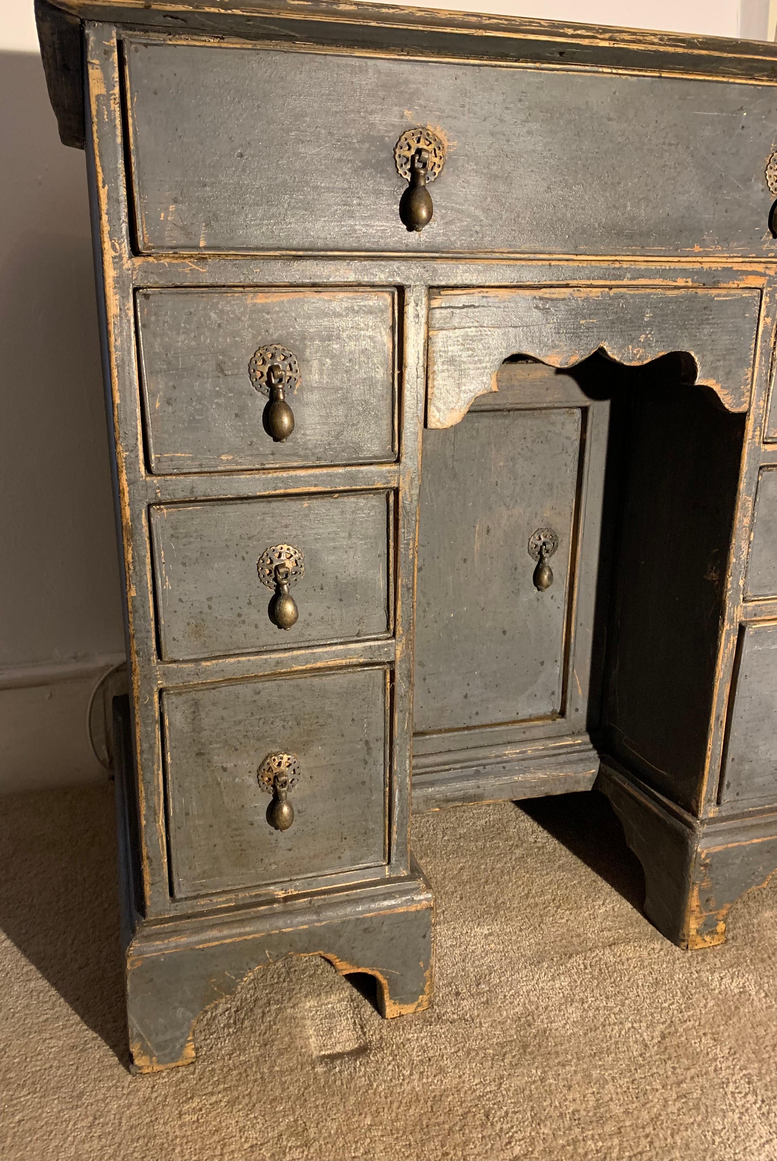 A charming diminutively sized English kneehole desk.
It was not originally made for a child but could be used as such as well as for an adult.
Repainted sympathetically in a dark blue/black colour.  The desk has useful deep side drawers (three on