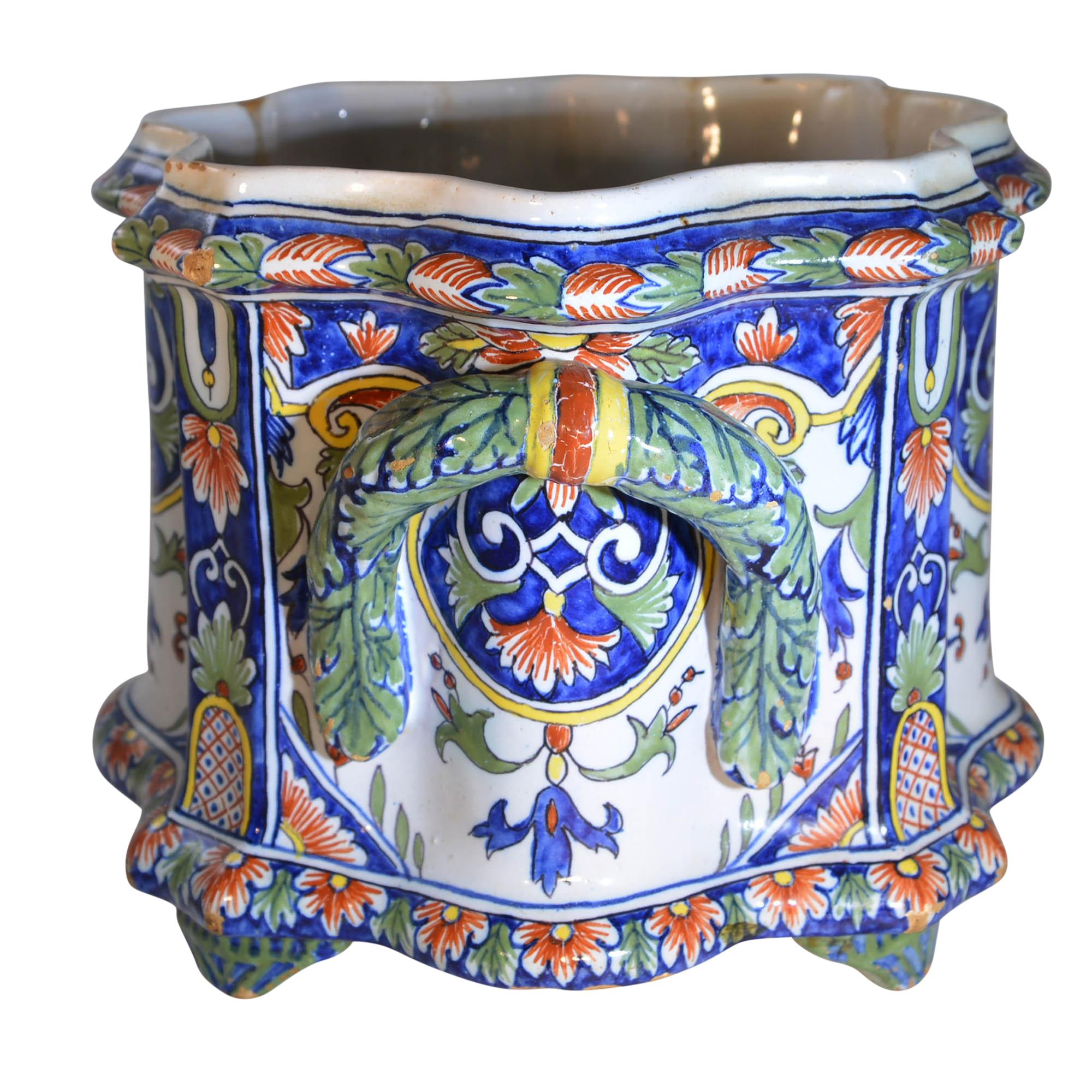 This colorful antique faience cachepot was sculpted in France, circa 1780. The hand painted decorations are carried around the jardinière and handles. The scalloped shape adds to the character of this unique pot. The arabesque motif in blue, red,