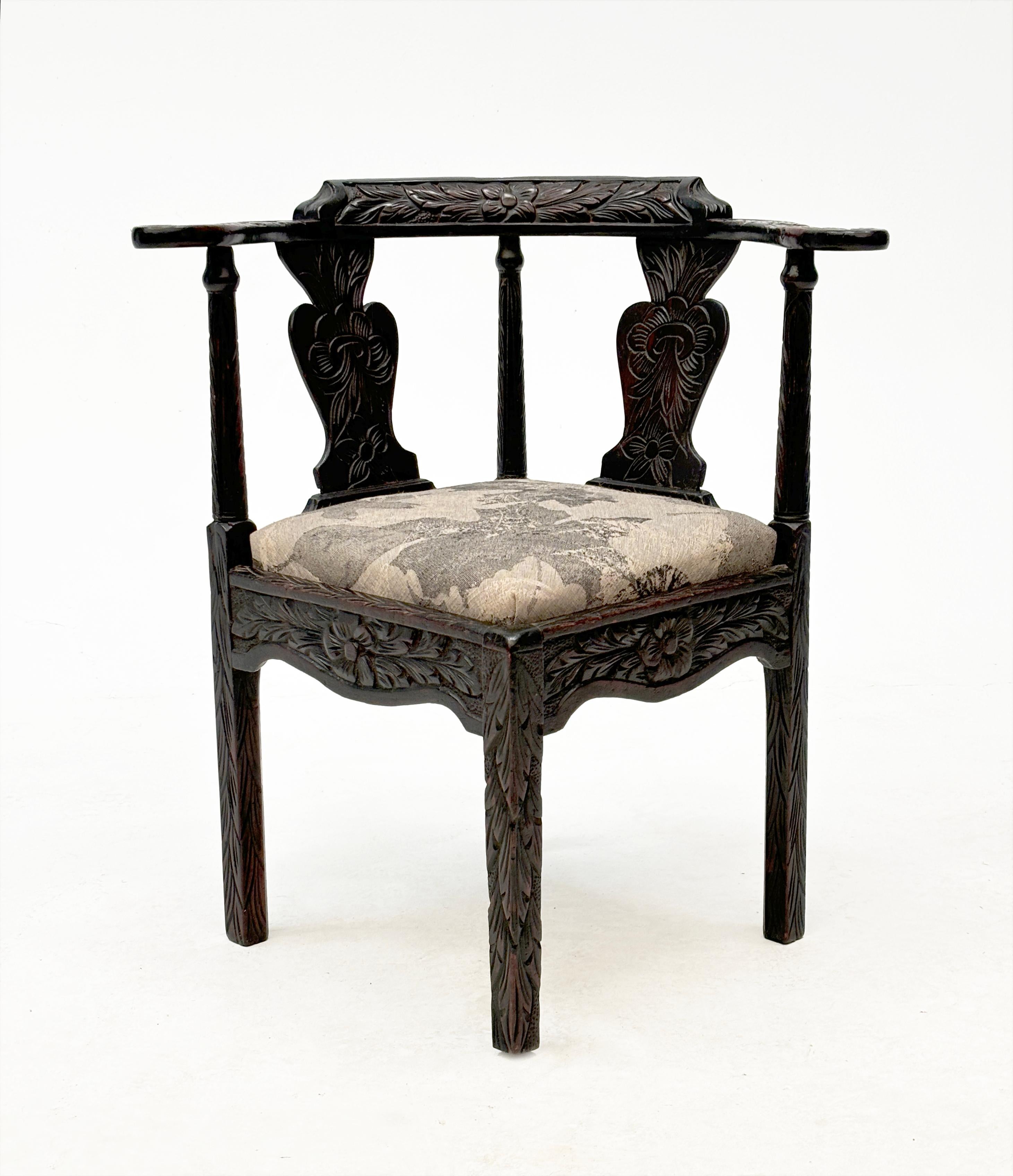 In the category of unique corner chairs, this circa 18th century carved oak corner chair featuring dark stain, floral chair rail, arms, and scalloped slanted splats is in the forefront as a one-of-a-kind piece. With ornately carved apron frame and