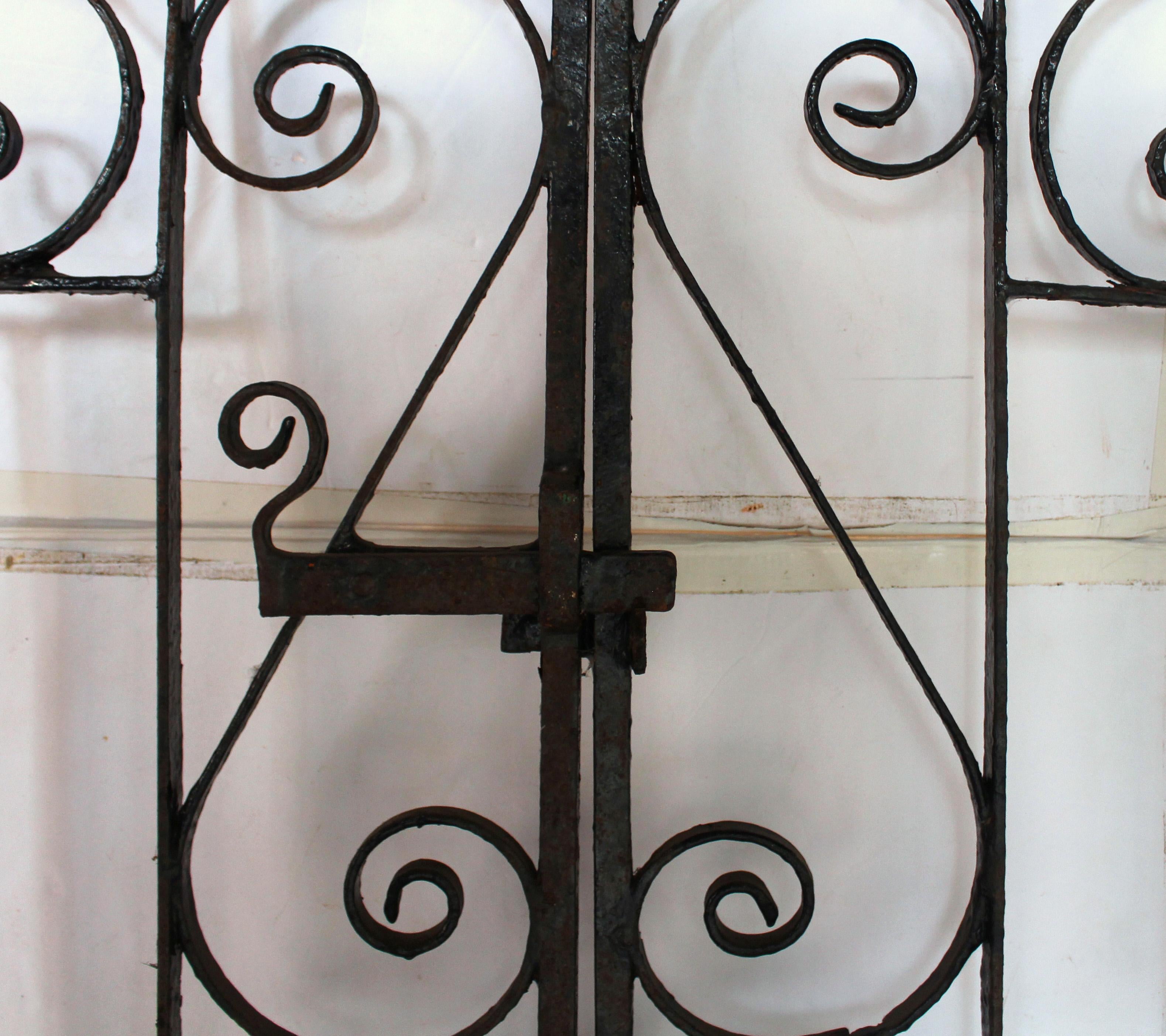 Circa 1900-1925 Pareja de puertas inglesas de hierro forjado para jardín o entrada de vehículos. Con pestillo y soportes accionables (sólo anillas de puerta). El sencillo diseño lineal se realza con cenefas y crestas de motivos curvos en S. Buen