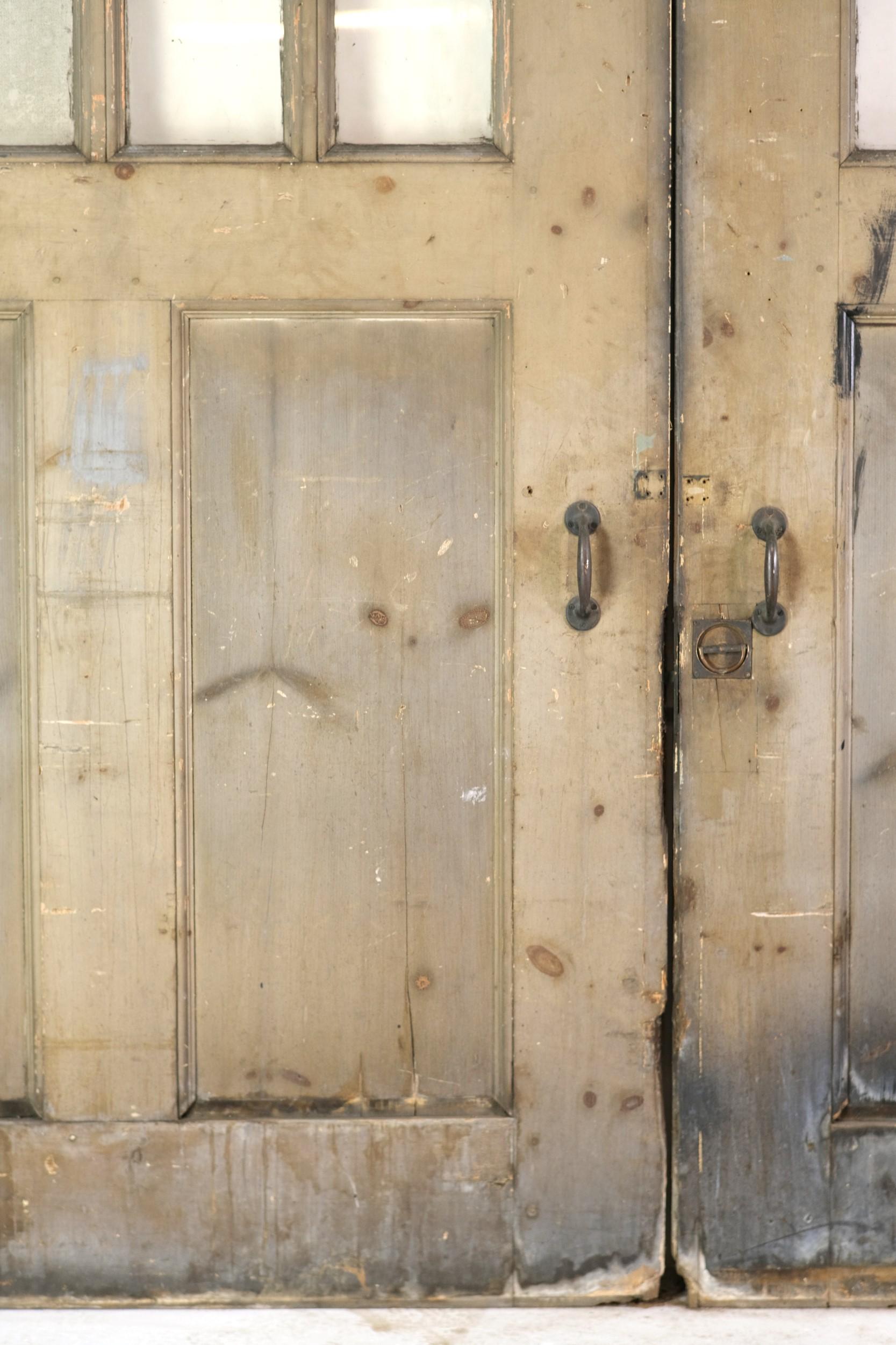 Turn of the century, Arts & Crafts double sliding oak doors with curved top 12 glass panes and 2 vertical wood panels on bottom. One side of the doors is painted a tannish green color and the other side is a gray color. These rare extra-large doors