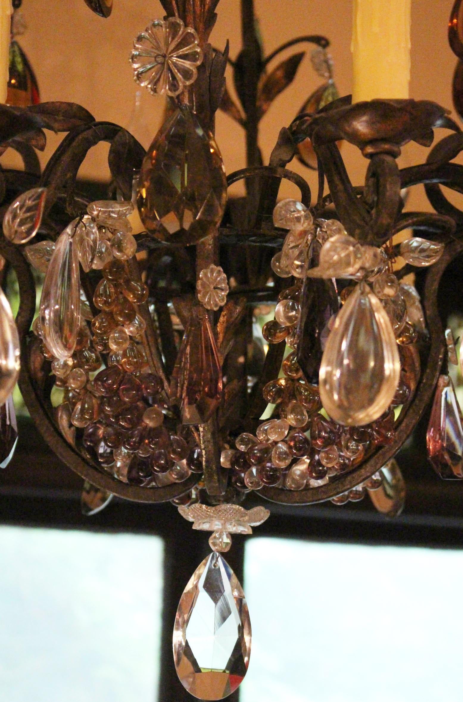 Lampadario a 8 luci in metallo nero a volute, elegante ed elaborato, con acanto in metallo dorato e bobeche in metallo dorato a forma di fiore, 1900 circa. Ricoperto di frutti, foglie e prismi colorati in vetro.
Circa 36