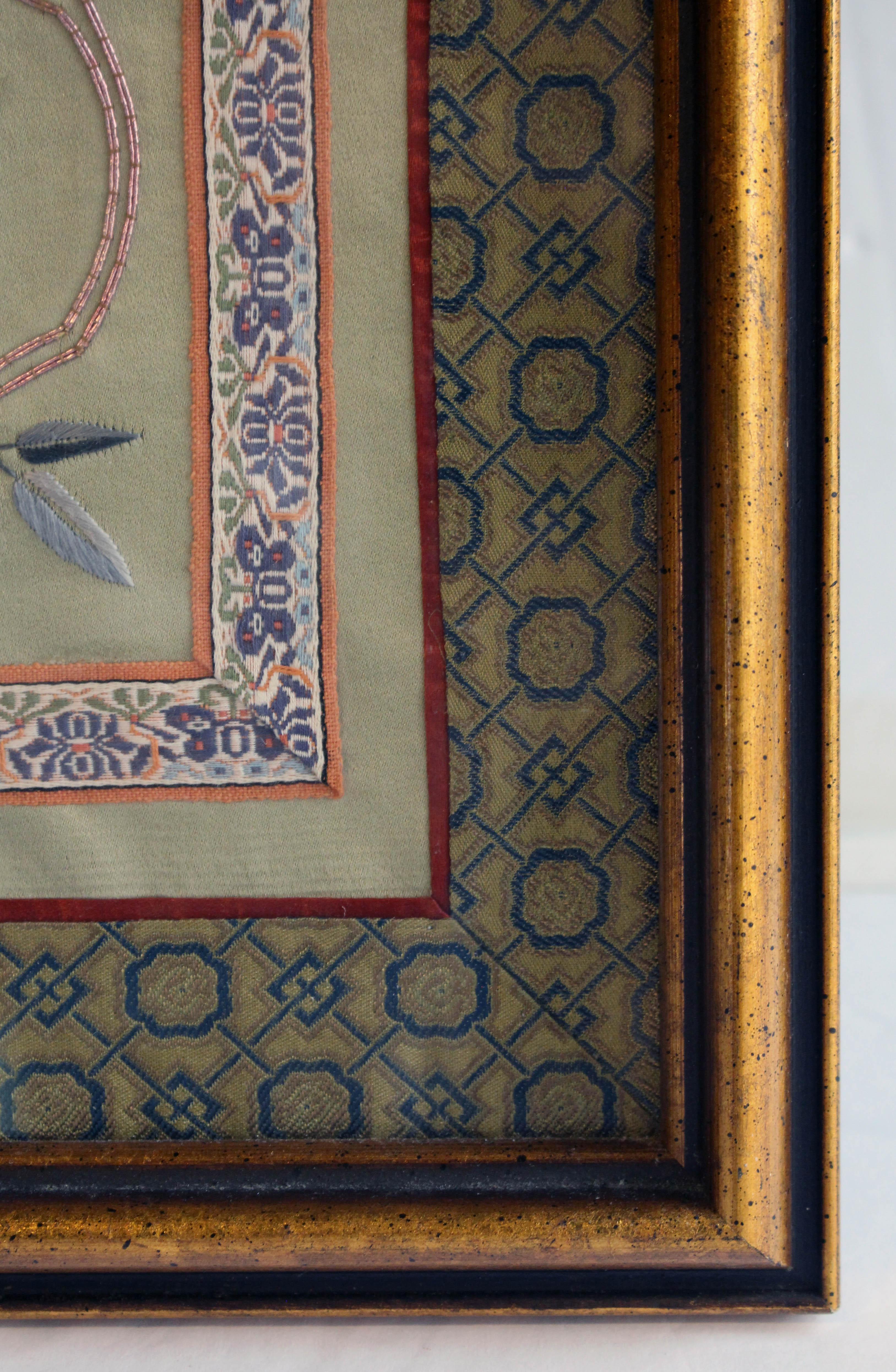 Circa 1900 Chinese silk panel in frame. Qing dynasty. Decorated with three cartouches set off in pink with gold thread, the smaller upper & lower ones with flowers & a butterfly; the middle larger one of an outcropping of flowers with a bird. Silk