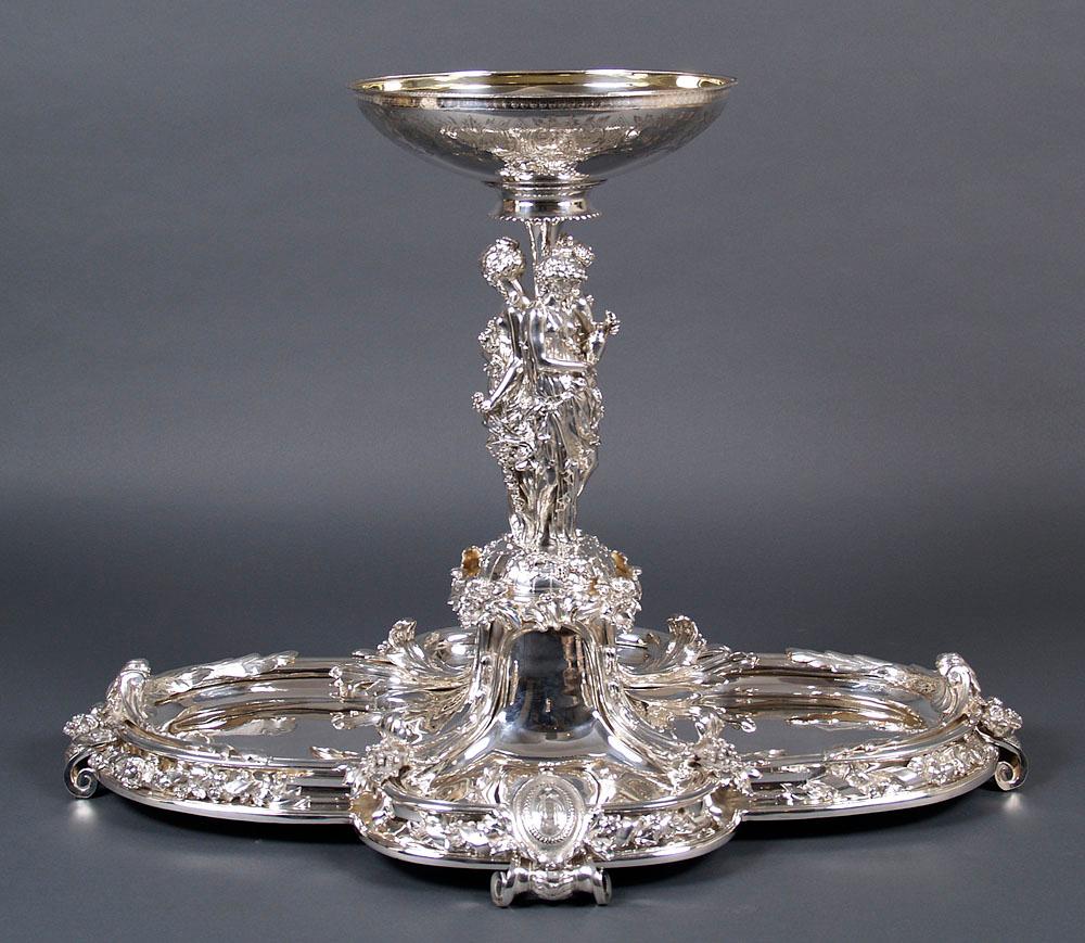 Christofle silver plated bronze table center (Surtout de table), circa 1900

Surtout de table, a large, decorative, high-quality table center. The base consists of four flat charms, two smaller ones at the front and at the back and two larger