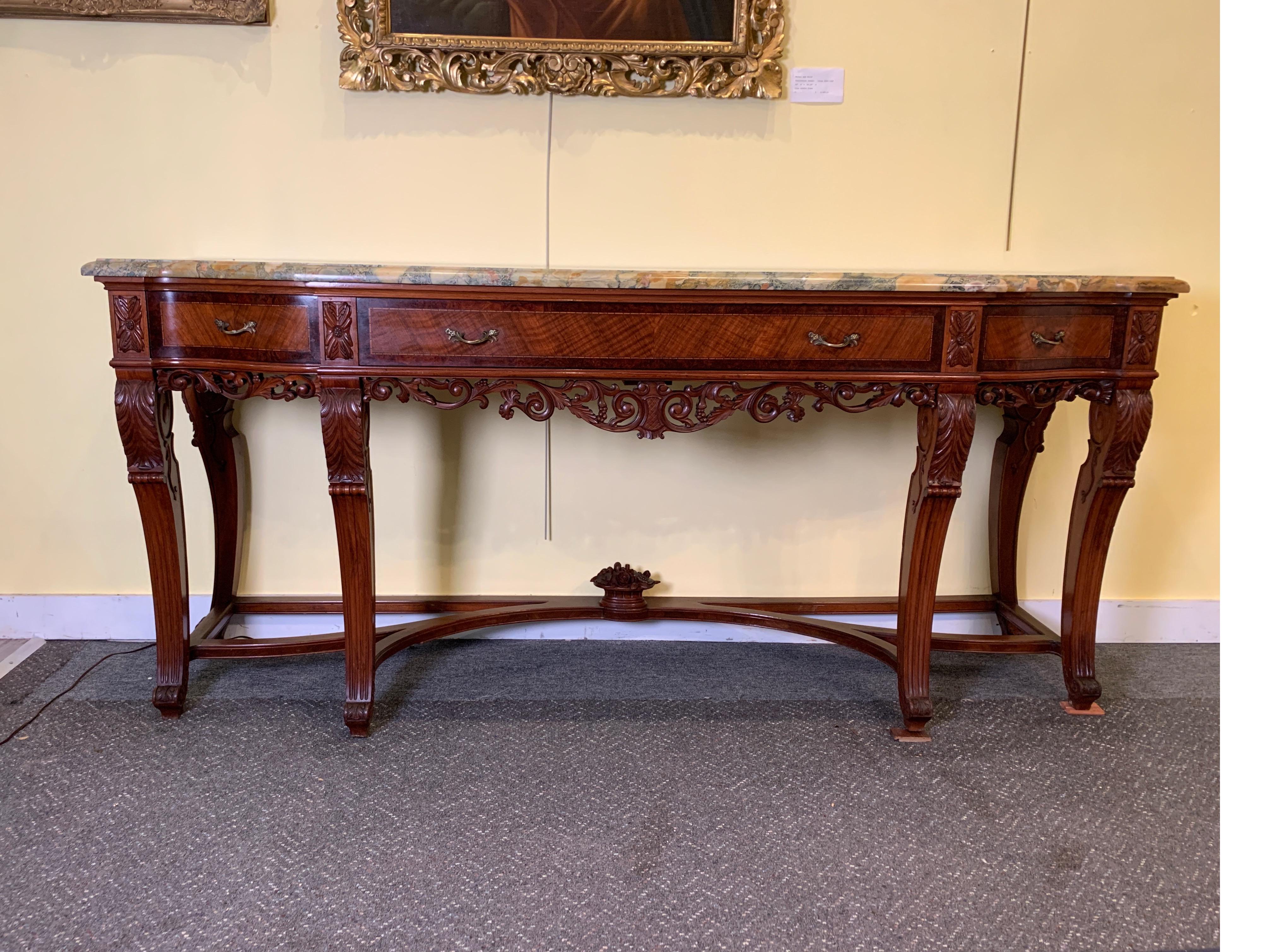 Continental carved walnut and inlaid marble-top console/sideboard, intricately carved solid walnut apron with shapely stretcher base with a central carved basket with finial, circa 1900
The console supported by six legs with acanthus leaves.